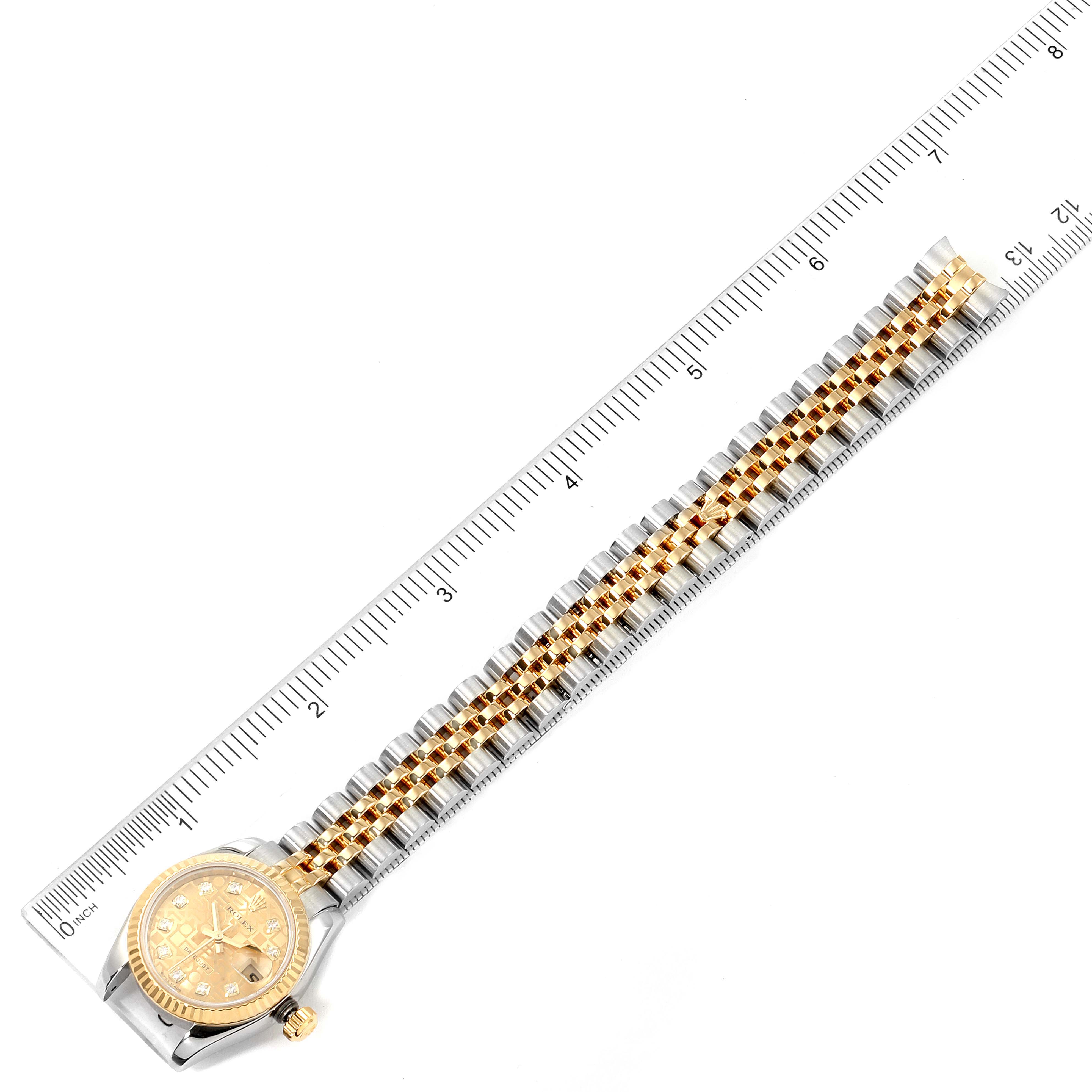 The Rolex Datejust 179173 Women's Steel and Gold (two tone) Champagne Dial 179173 Women's Steel and Gold (two tone) Champagne Dial watch is shown from a top-down angle, displaying its dial, bezel, and bracelet next to a ruler for scale.