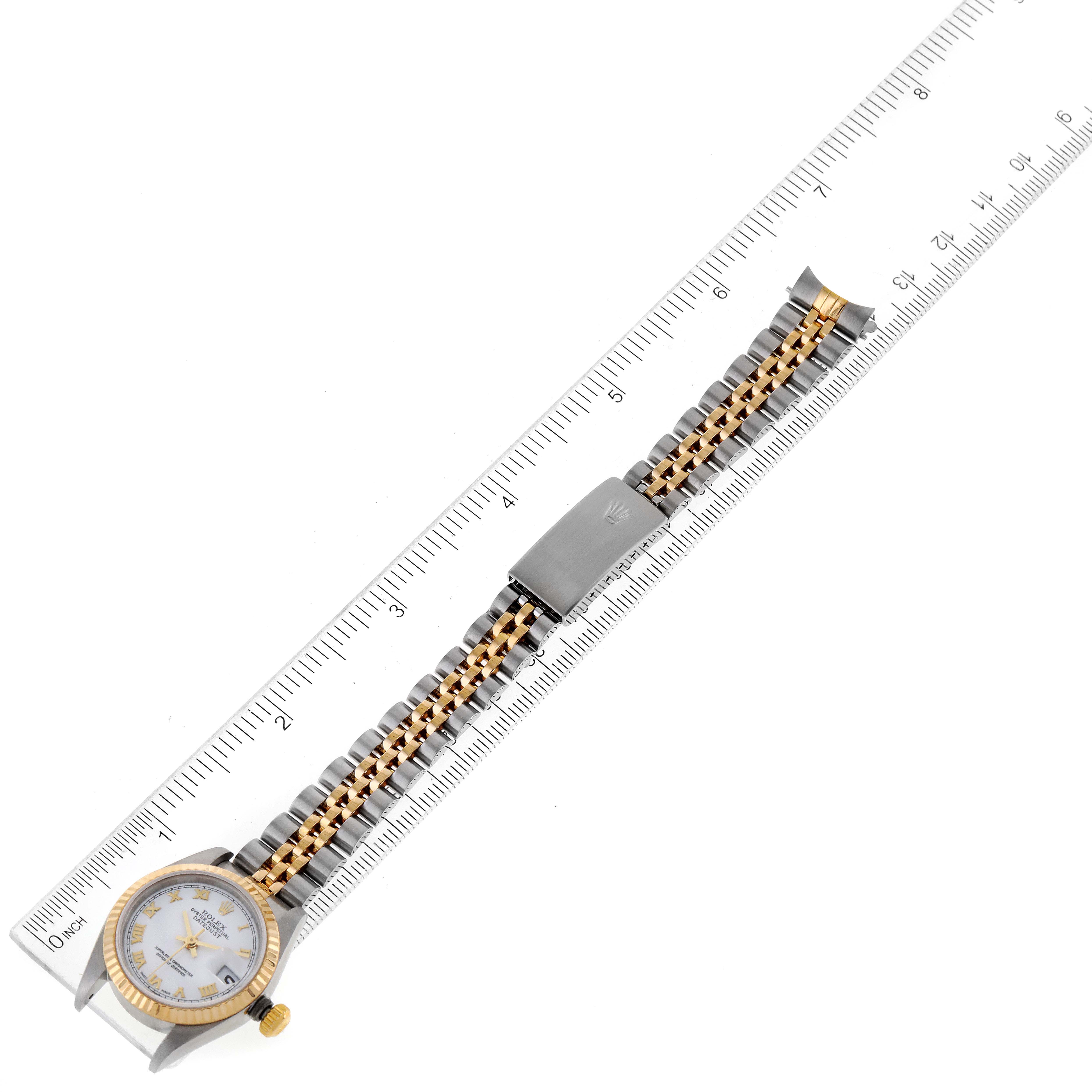 The image shows a Rolex Datejust 79173 Women's Steel and Gold (two tone) White Dial 79173 Women's Steel and Gold (two tone) White Dial watch laid front-facing on a ruler, highlighting its face, bezel, bracelet, and clasp.