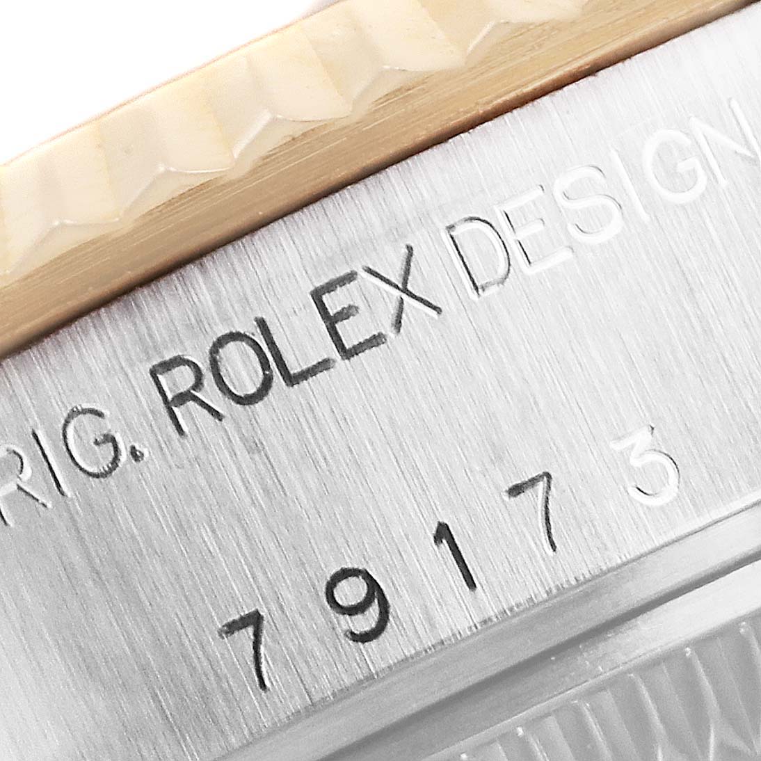 This close-up image shows the engraved side of a Rolex Datejust 79173 Women's Steel and Gold (two tone) White Dial 79173 Women's Steel and Gold (two tone) White Dial watch case, displaying the brand name and serial number.
