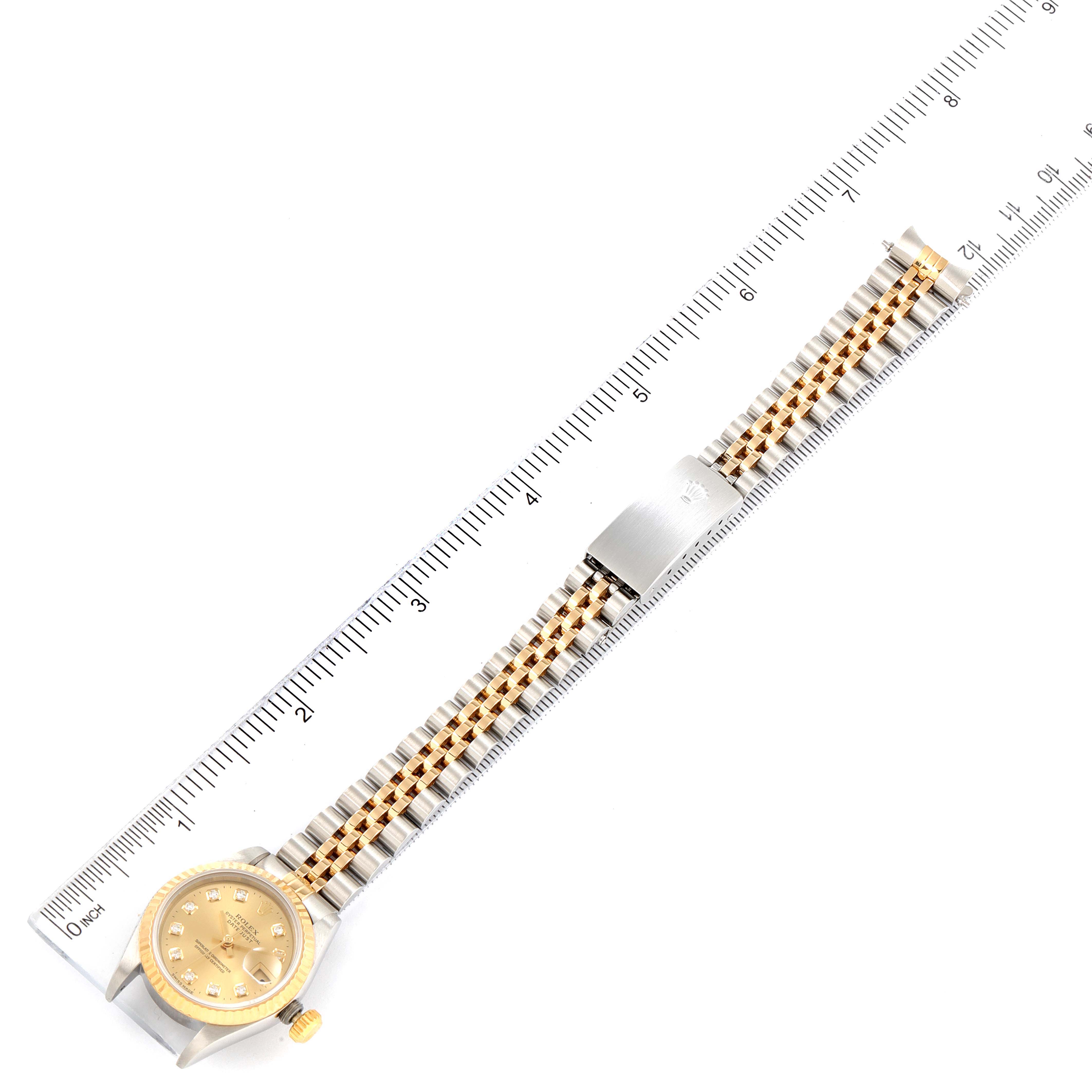 This image shows a top-down view of a Rolex Datejust 69173 Women
s Steel and Gold (two tone) Champagne Dial 69173 Women
s Steel and Gold (two tone) Champagne Dial watch, displaying its face and metal bracelet alongside a measuring scale.