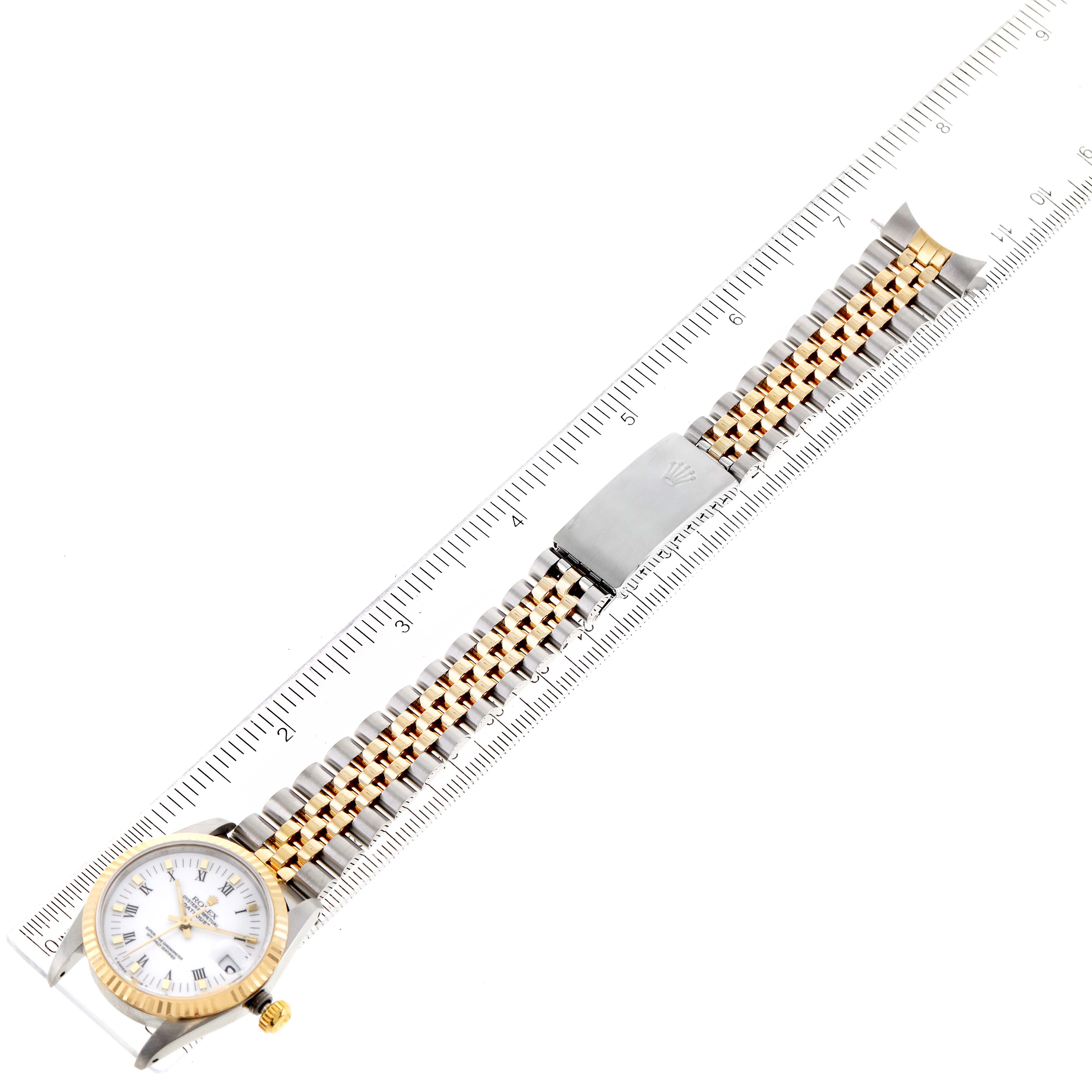 The image shows a full-length view of a Rolex Mid-Size 68273 Women
s Steel and Gold (two tone) White Dial 68273 Women
s Steel and Gold (two tone) White Dial watch, highlighting its dial, bracelet, and clasp with a ruler for scale.