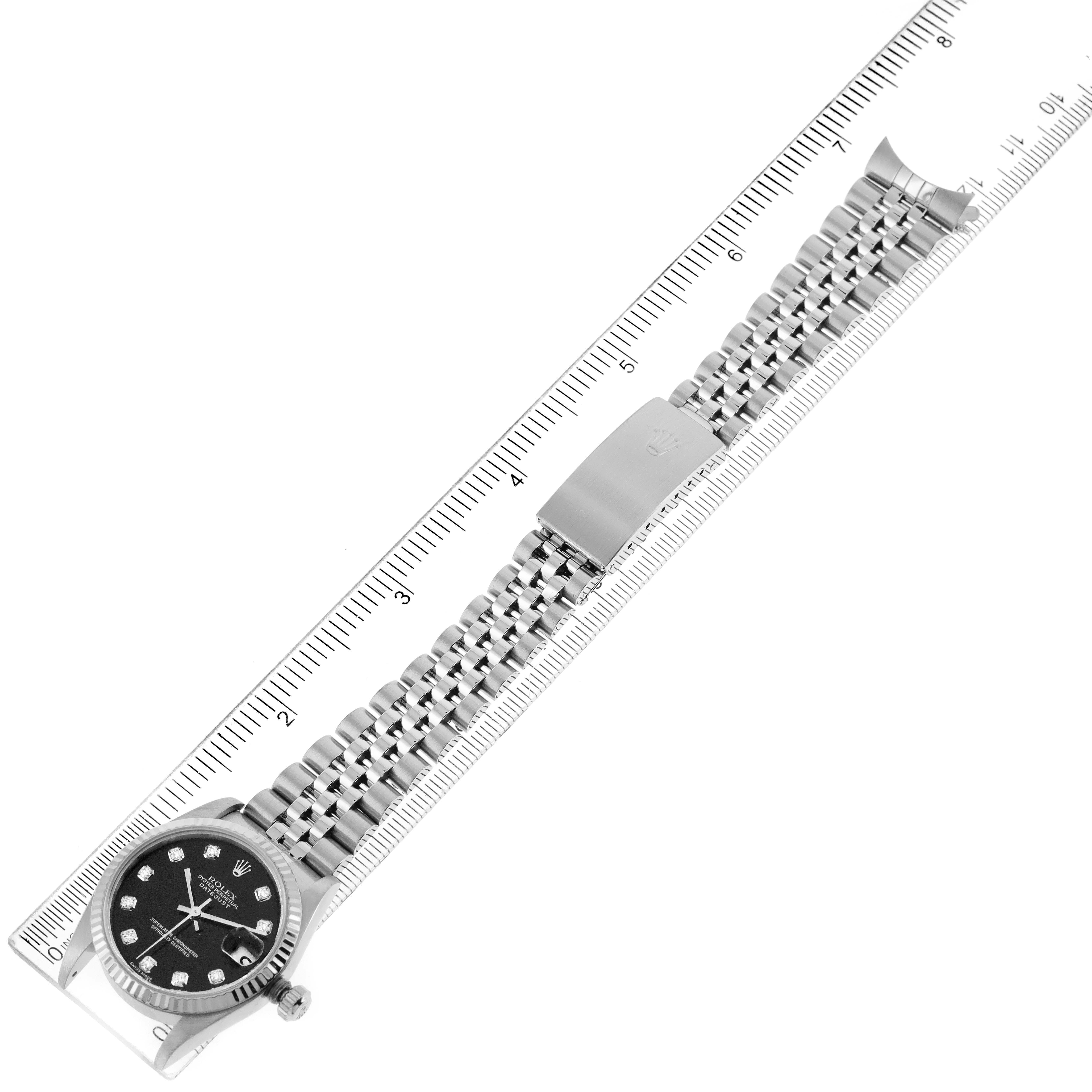 The Rolex Datejust 78274 Women's Stainless Steel Black Dial 78274 Women's Stainless Steel Black Dial watch is displayed flat, with its face, bracelet, and clasp visible against a ruler for scale.