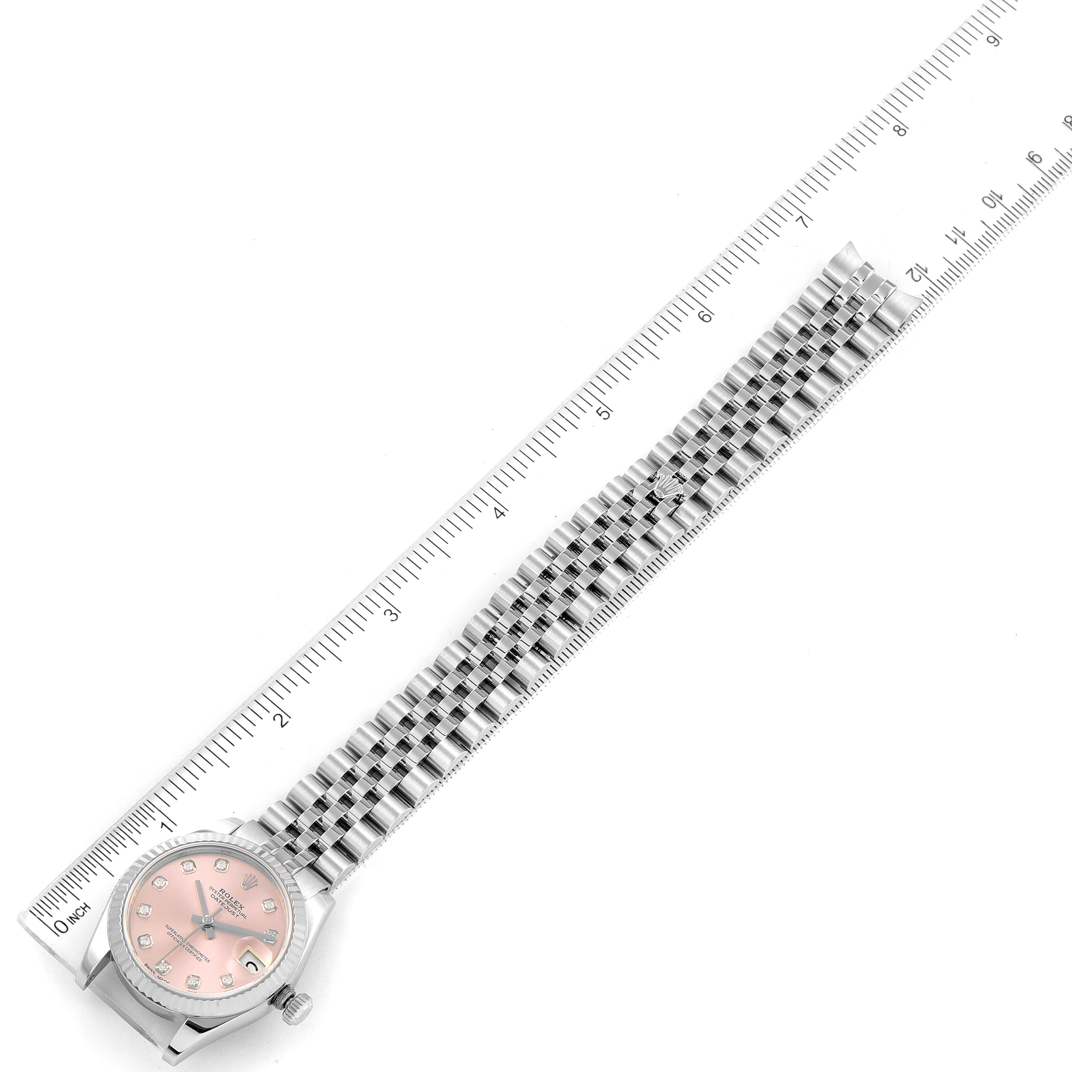 The image shows a Rolex Mid-Size 178274 Women's Stainless Steel Pink Dial 178274 Women's Stainless Steel Pink Dial watch with a pink dial and a metal bracelet, placed alongside a ruler for measuring.