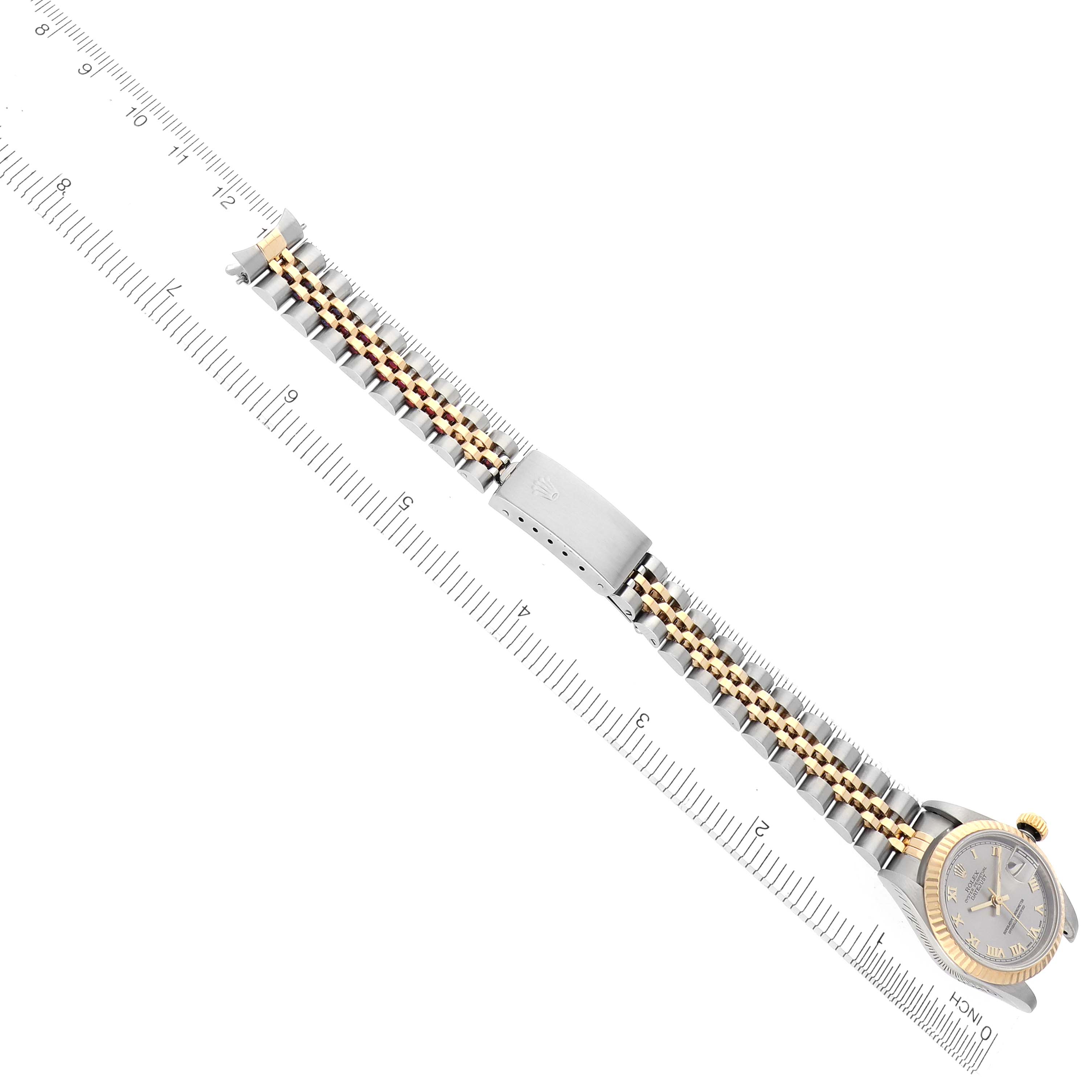 The Rolex Datejust 69173 Women's Steel and Gold (two tone) Silver Dial 69173 Women's Steel and Gold (two tone) Silver Dial watch is shown laid flat, highlighting the bracelet and clasp, with a ruler for scale.