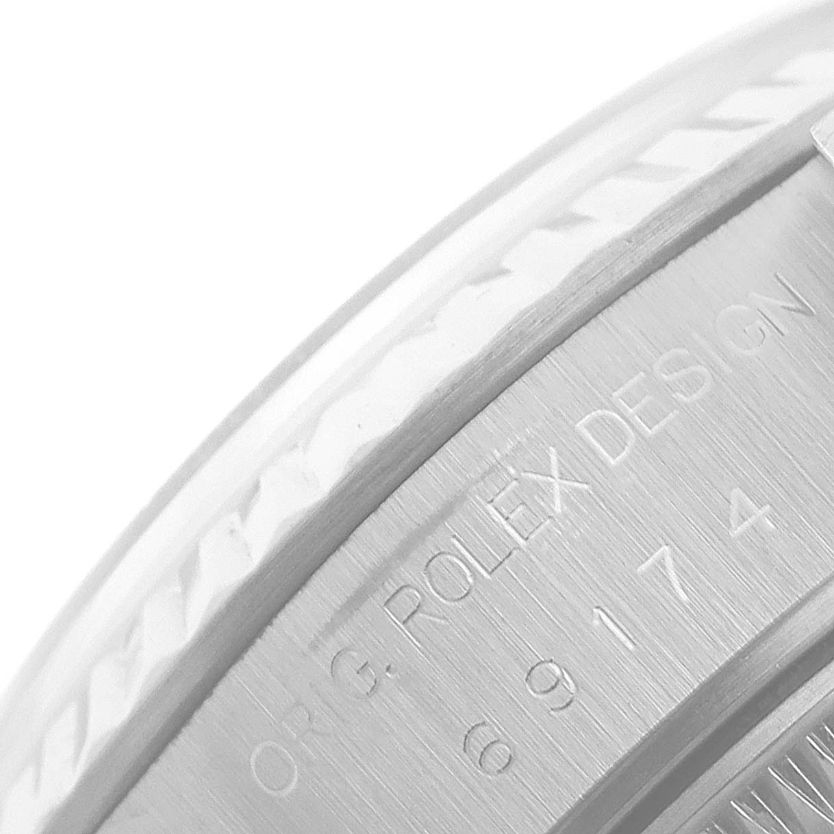 The image shows a close-up of the side of the Rolex Datejust 69174 Women
s Stainless Steel Silver Dial 69174 Women
s Stainless Steel Silver Dial watch, showcasing the engraved branding and part of the bezel.