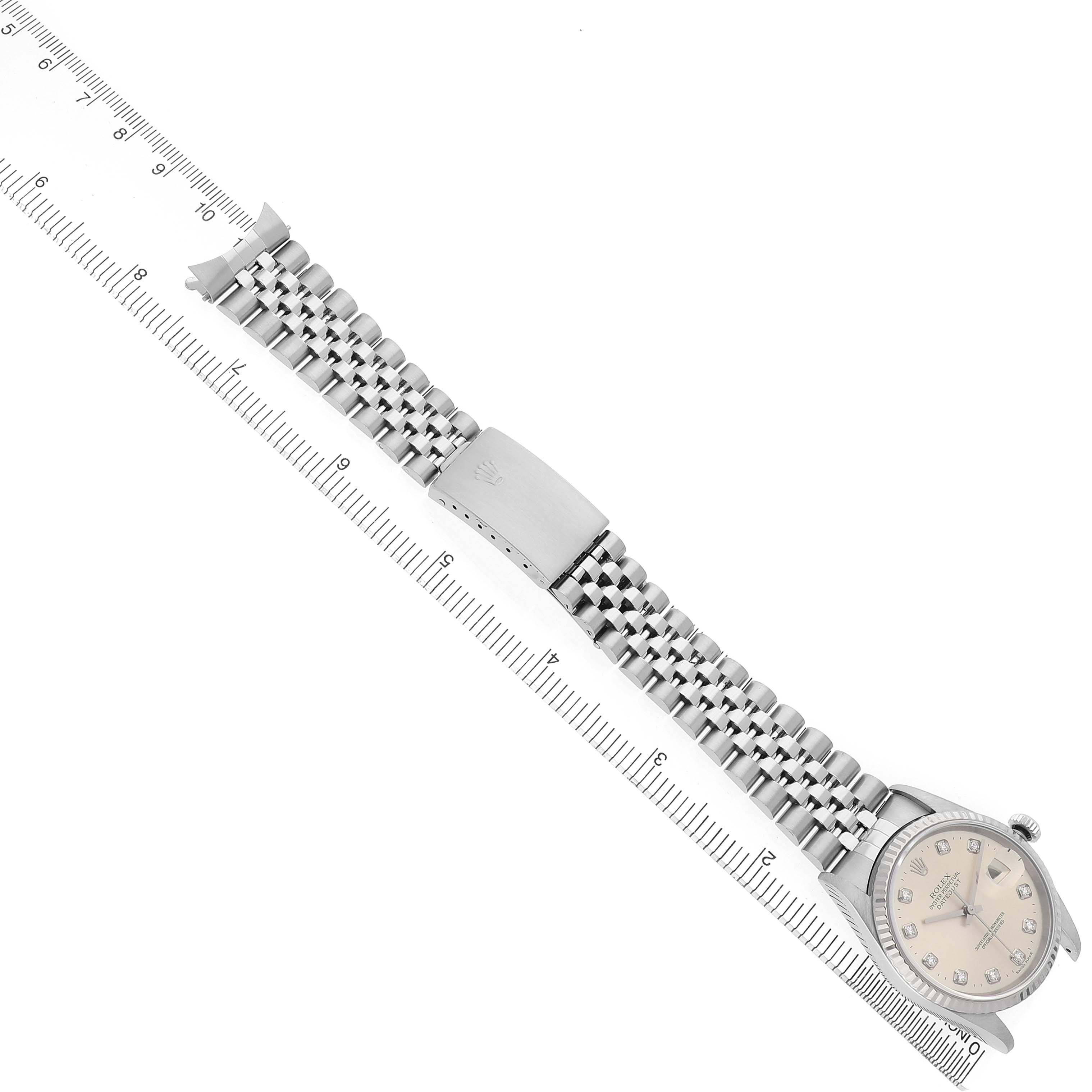 The Rolex Datejust 16234 Men's Stainless Steel Silver Dial watch is shown diagonally, displaying the dial, case, and metal bracelet alongside a ruler for scale.