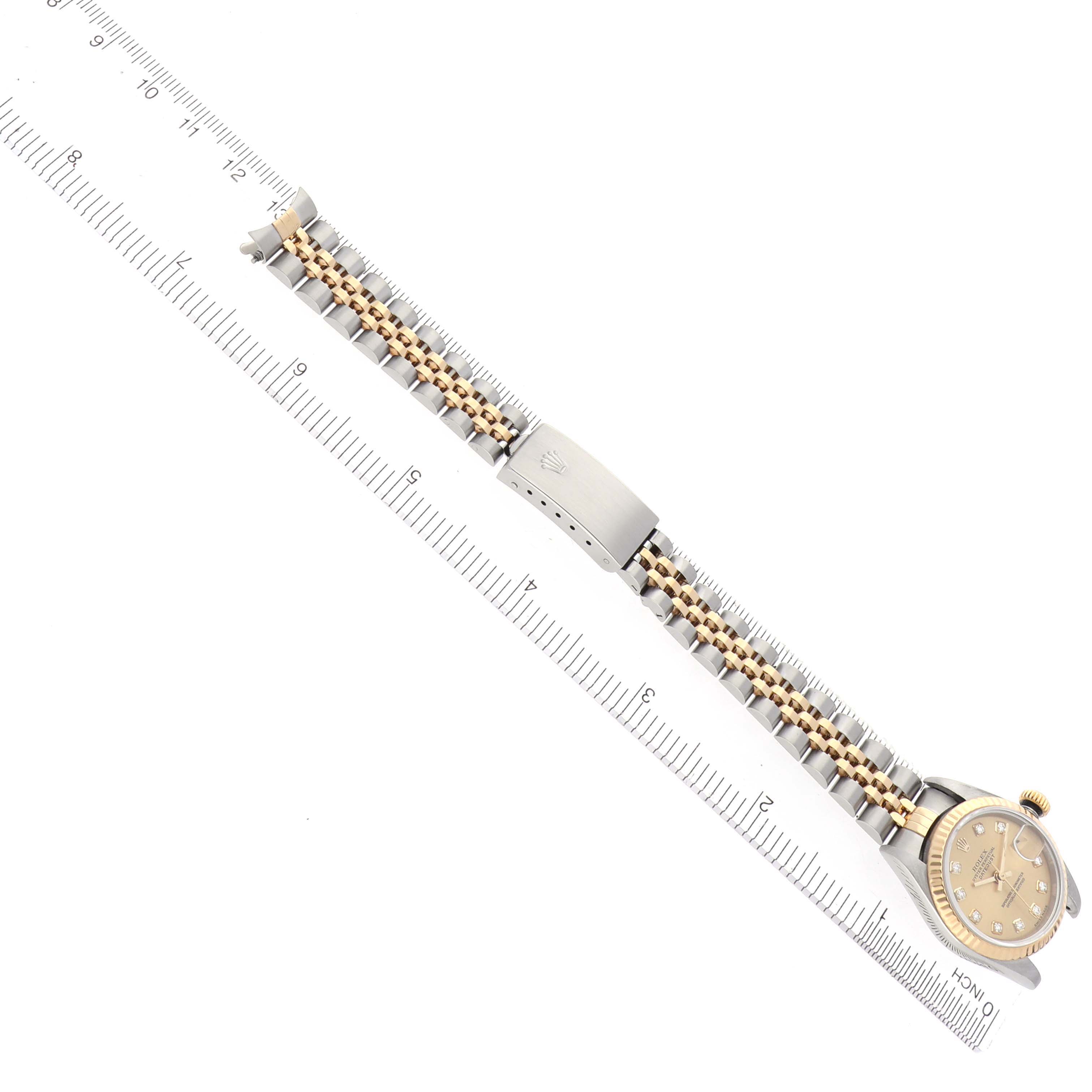 The Rolex Datejust 79173 Women's Steel and Gold (two tone) Champagne Dial 79173 Women's Steel and Gold (two tone) Champagne Dial watch is shown from a top view, displaying the face, bracelet, and clasp, aligned with a ruler.