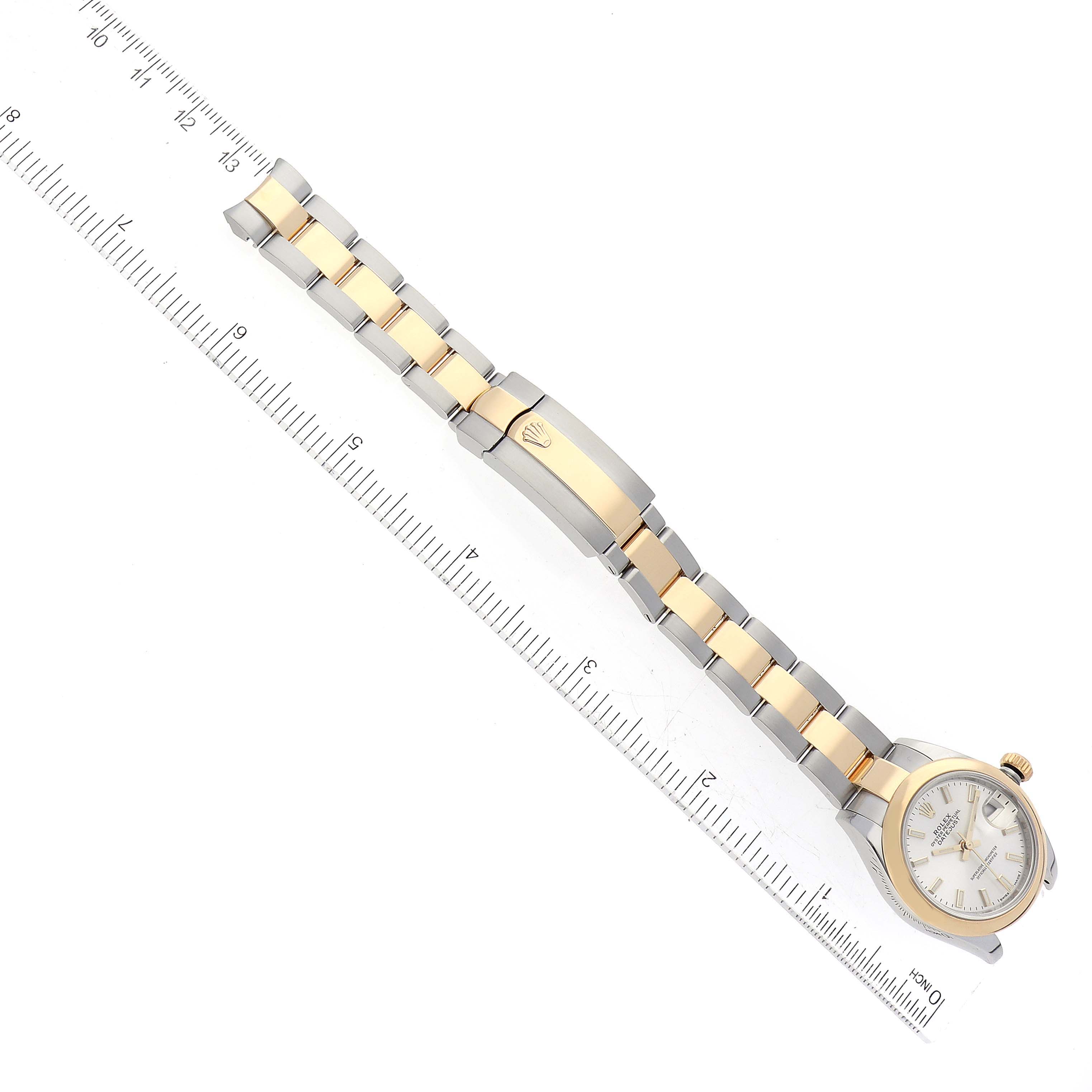 The Rolex Datejust 279163 Women's Steel and Gold (two tone) Silver Dial 279163 Women's Steel and Gold (two tone) Silver Dial watch is shown from a top-down angle, displaying its band and clasp next to a measuring ruler.