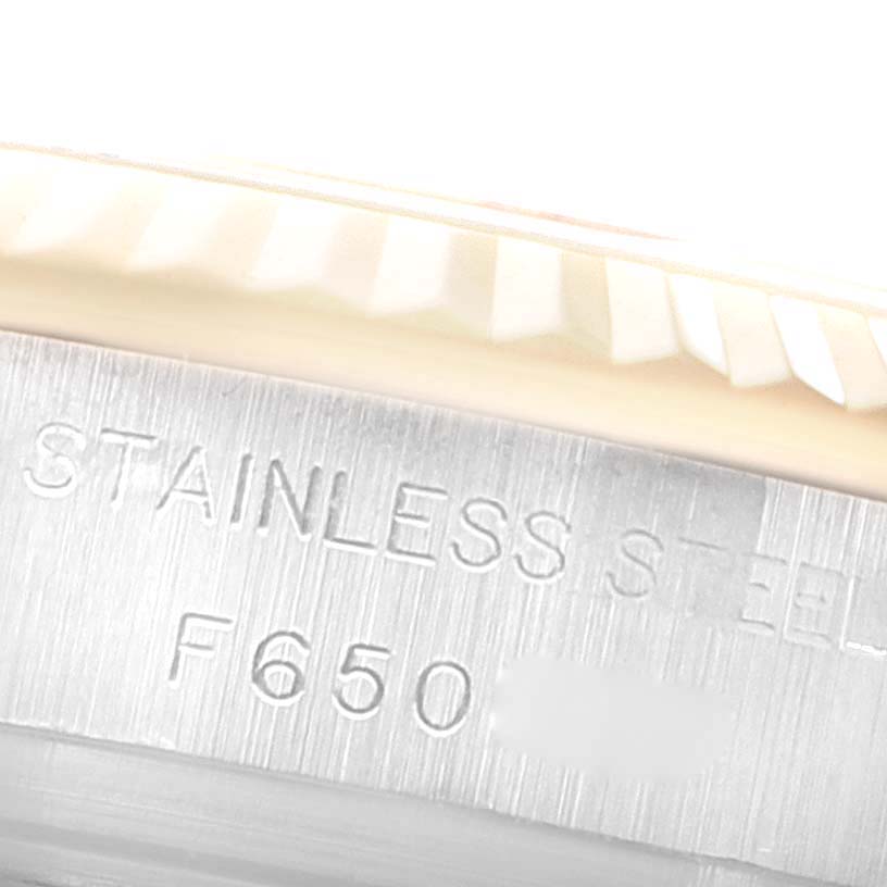 This image of a Rolex Datejust 179173 Women's Steel and Gold (two tone) White Dial 179173 Women's Steel and Gold (two tone) White Dial watch shows a close-up of the fluted bezel and inscription on the case, indicating "STAINLESS STEEL".