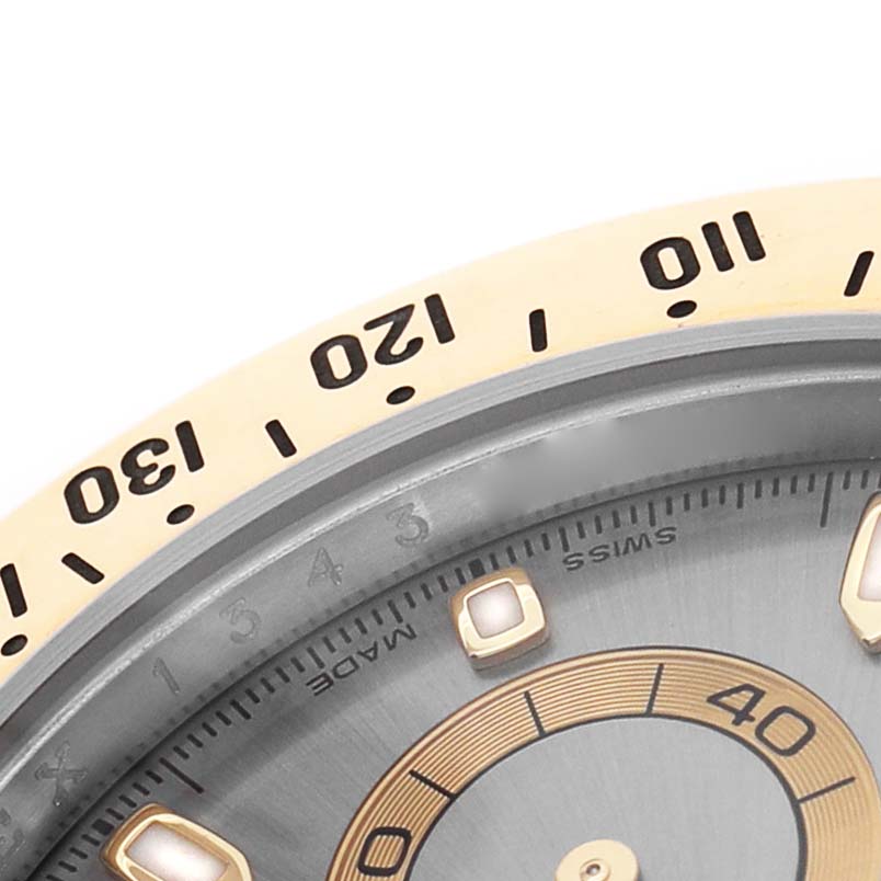The image shows a close-up of the bezel and part of the dial of a Rolex Daytona 116523 Men's Steel and Gold (two tone) Silver Dial watch.