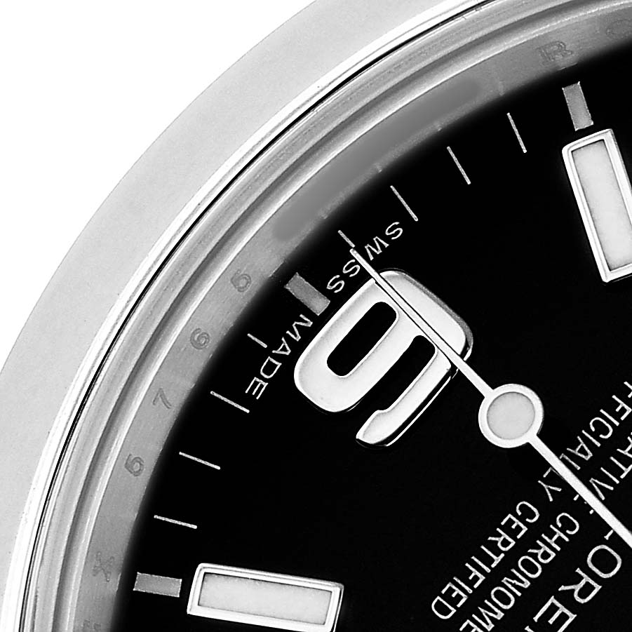 The image shows a close-up of the dial and bezel of a Rolex Explorer 214270 Men's Stainless Steel Black Dial watch, focusing on the numerals and part of the minute hand.