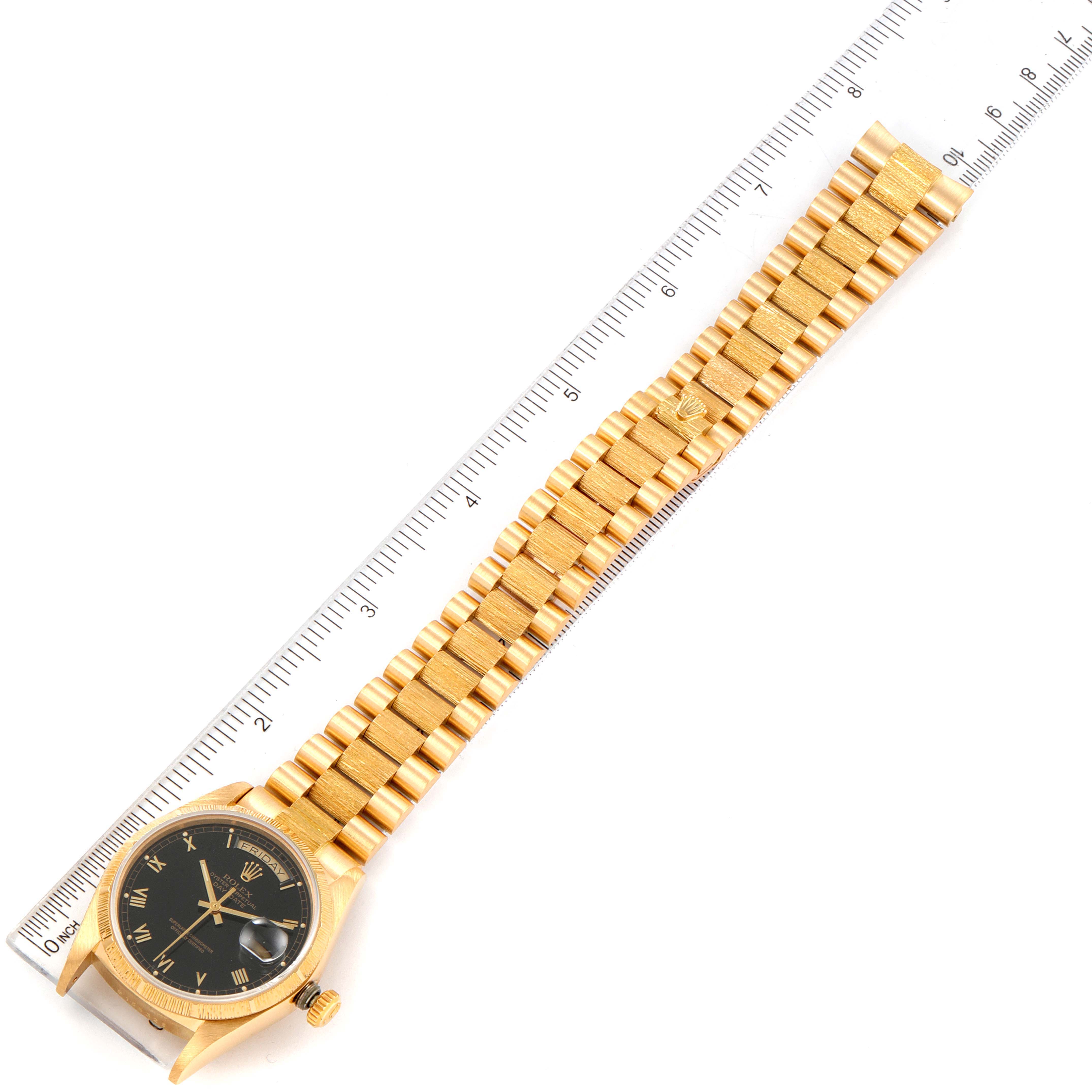 The image shows a Rolex President 18078 Men's Yellow Gold Black Dial 18078 Men's Yellow Gold Black Dial model watch laid flat alongside a ruler, displaying its face, band, and clasp at an angled view.