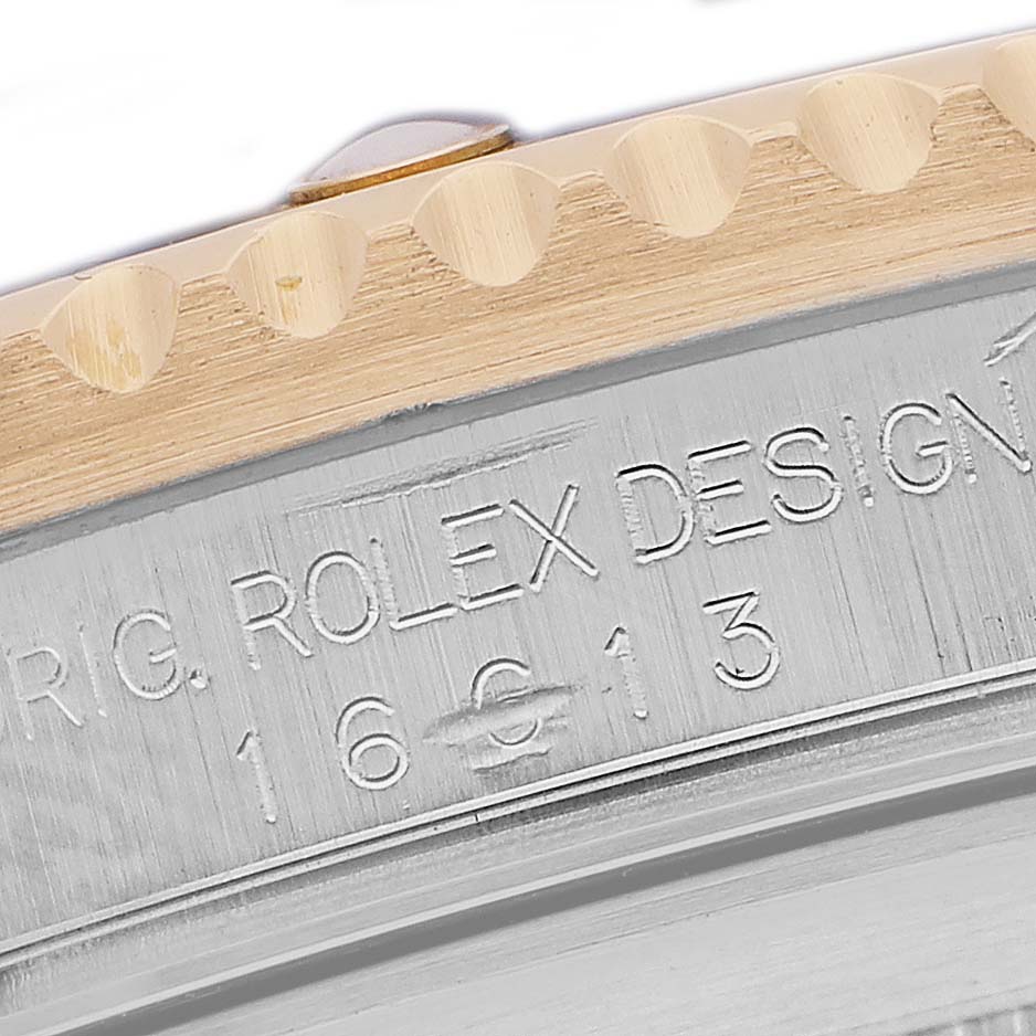 The image shows a close-up of the case side, focusing on the bezel and engravings of a Rolex Submariner 16613 Men's Steel and Gold (two tone) Blue Dial.