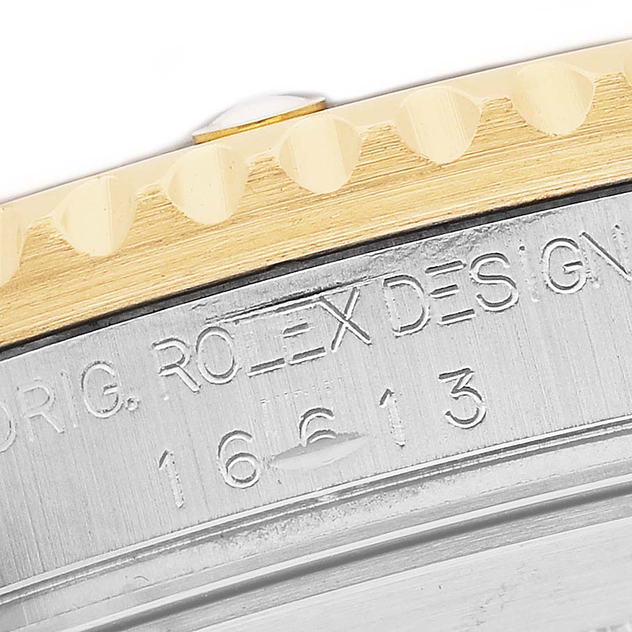 The image shows the engraved side of the Rolex Submariner 16613 Men's Steel and Gold (two tone) Silver Dial's case with a focus on the model number and design details.