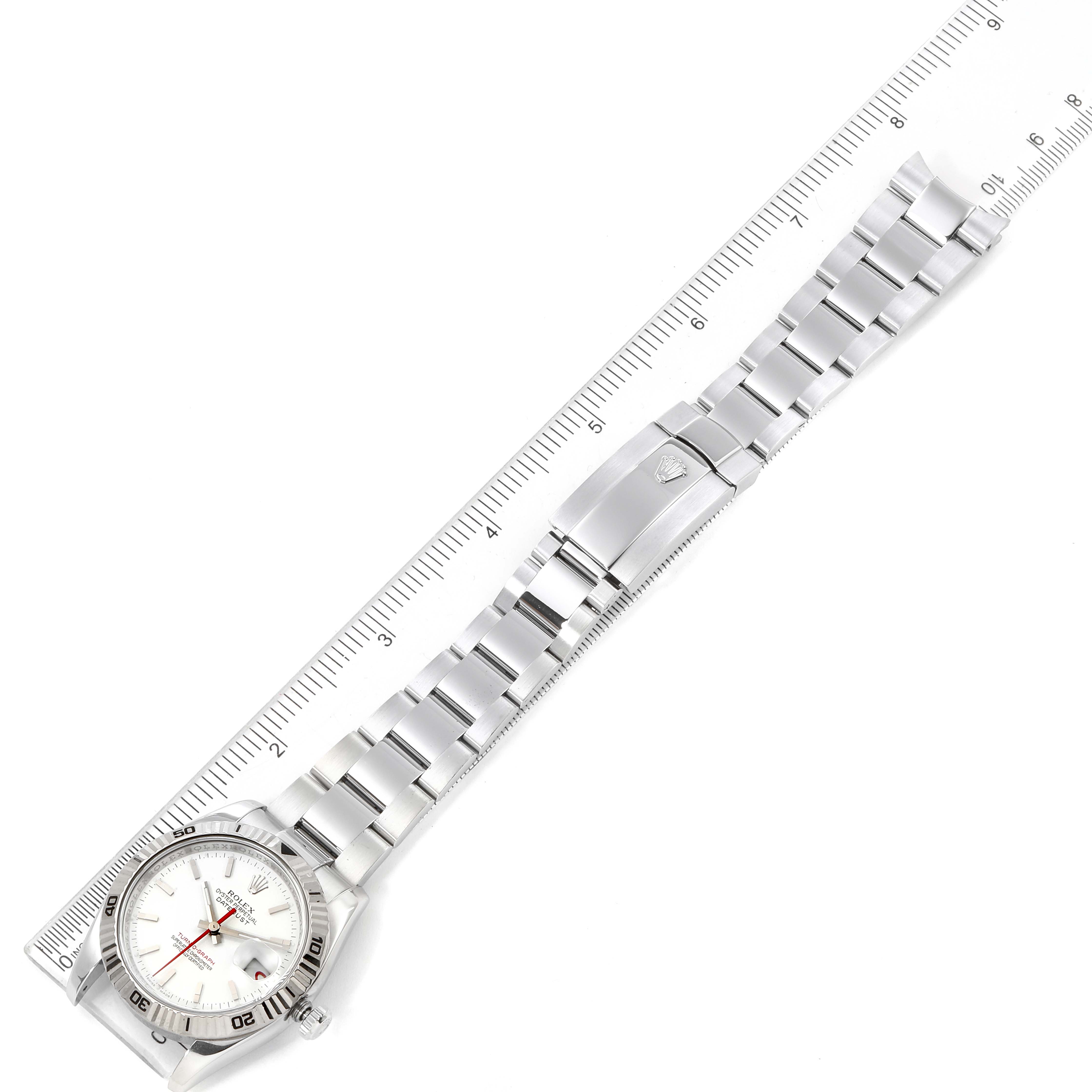 The image shows the top view of a Rolex Turn-o-Graph 116264 Men
s Stainless Steel White Dial 116264 Men
s Stainless Steel White Dial watch, displaying its silver bracelet and clasp, alongside a measuring ruler.