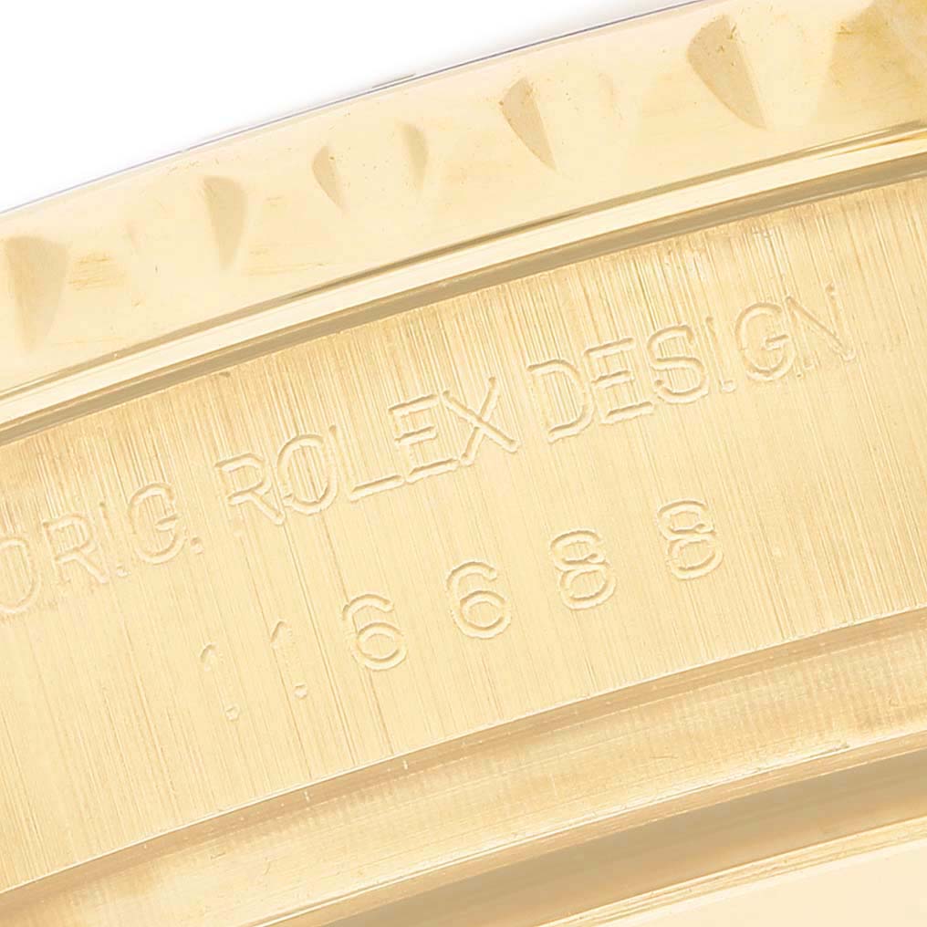 The image shows an angled close-up of the gold bezel edge and engraved serial reference of the Rolex Yacht-Master 116688 Men's Yellow Gold White Dial watch.