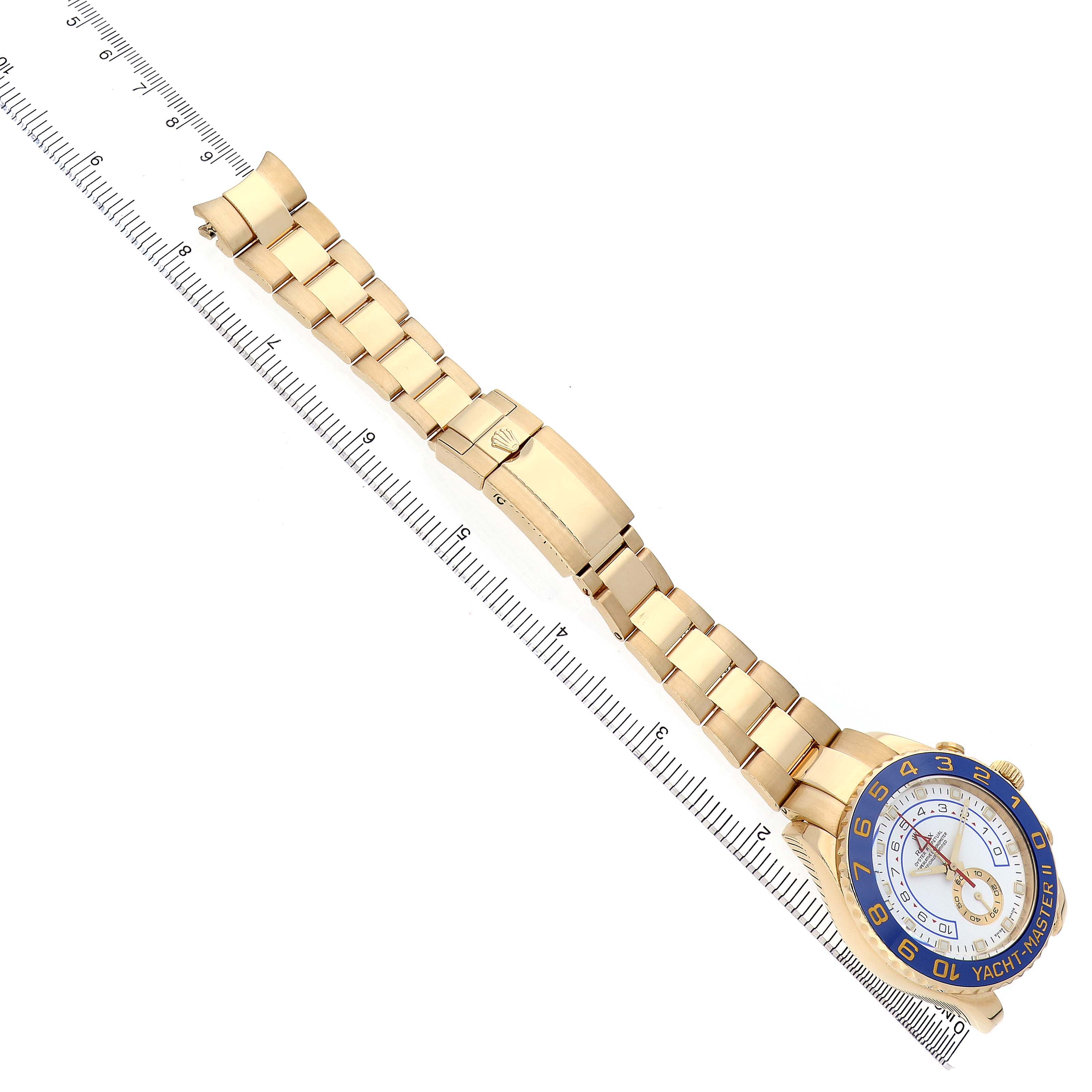 The Rolex Yacht-Master 116688 Men's Yellow Gold White Dial watch is shown at an angle displaying its face and full bracelet alongside a ruler for scale.