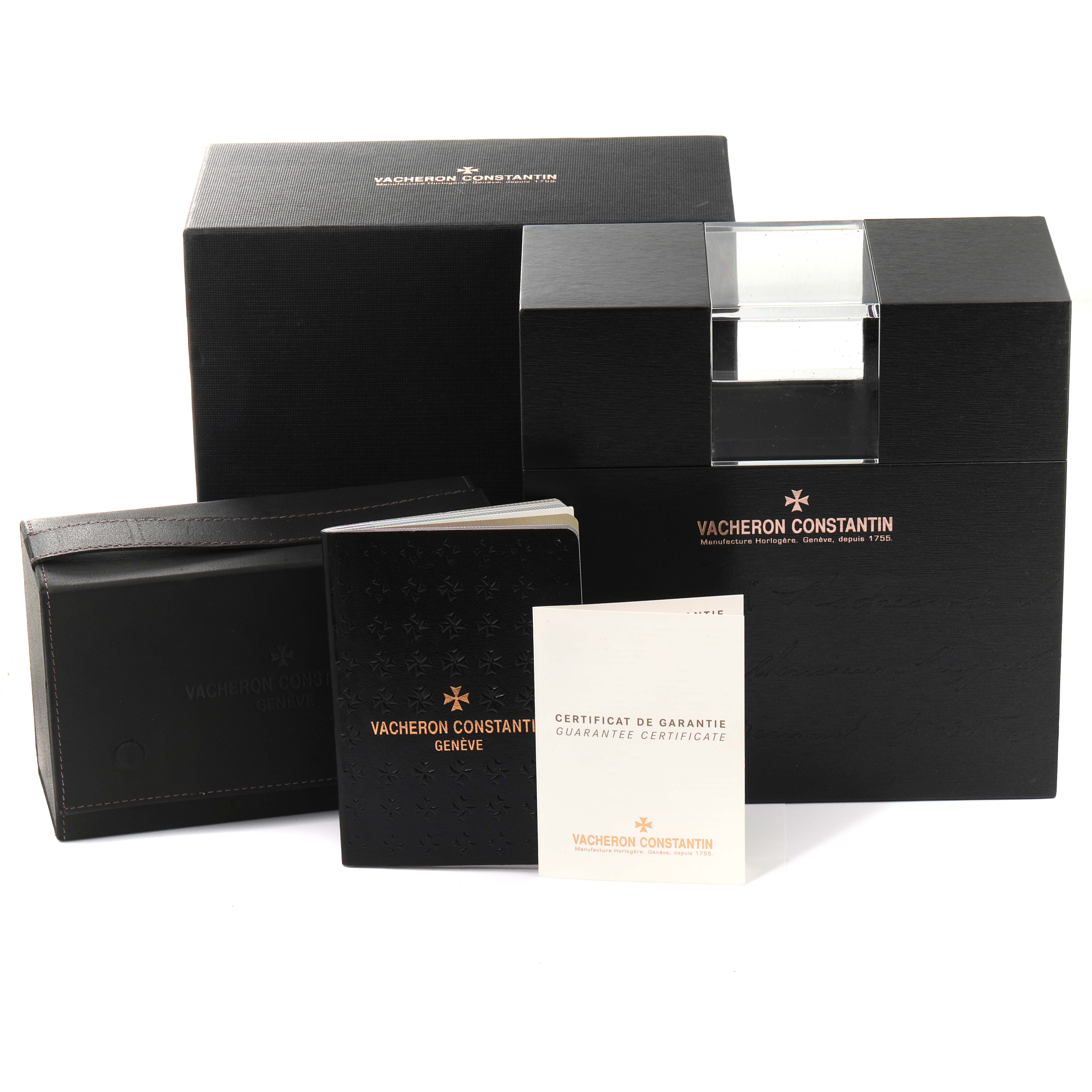 The image shows the Vacheron Constantin Overseas 47560/000R-9672 Women's Rose Gold Silver Dial 47560/000R-9672 Women's Rose Gold Silver Dial watch packaging, including boxes and booklets, viewed from the front.