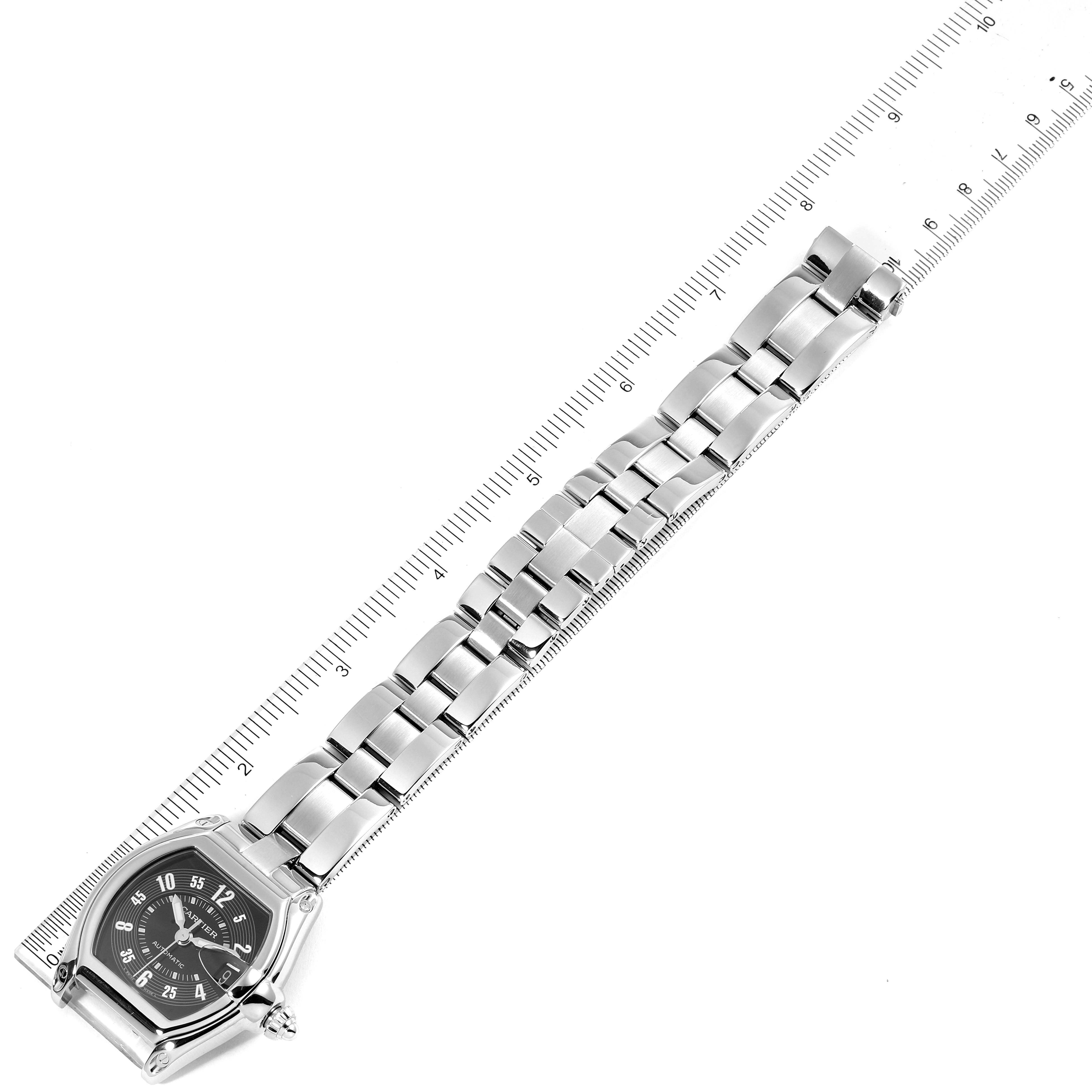 This image shows the Cartier Roadster W62004V3 Men's Stainless Steel Black Dial W62004V3 Men's Stainless Steel Black Dial watch laid flat, displaying its face, bracelet, and clasp alongside a measuring scale.