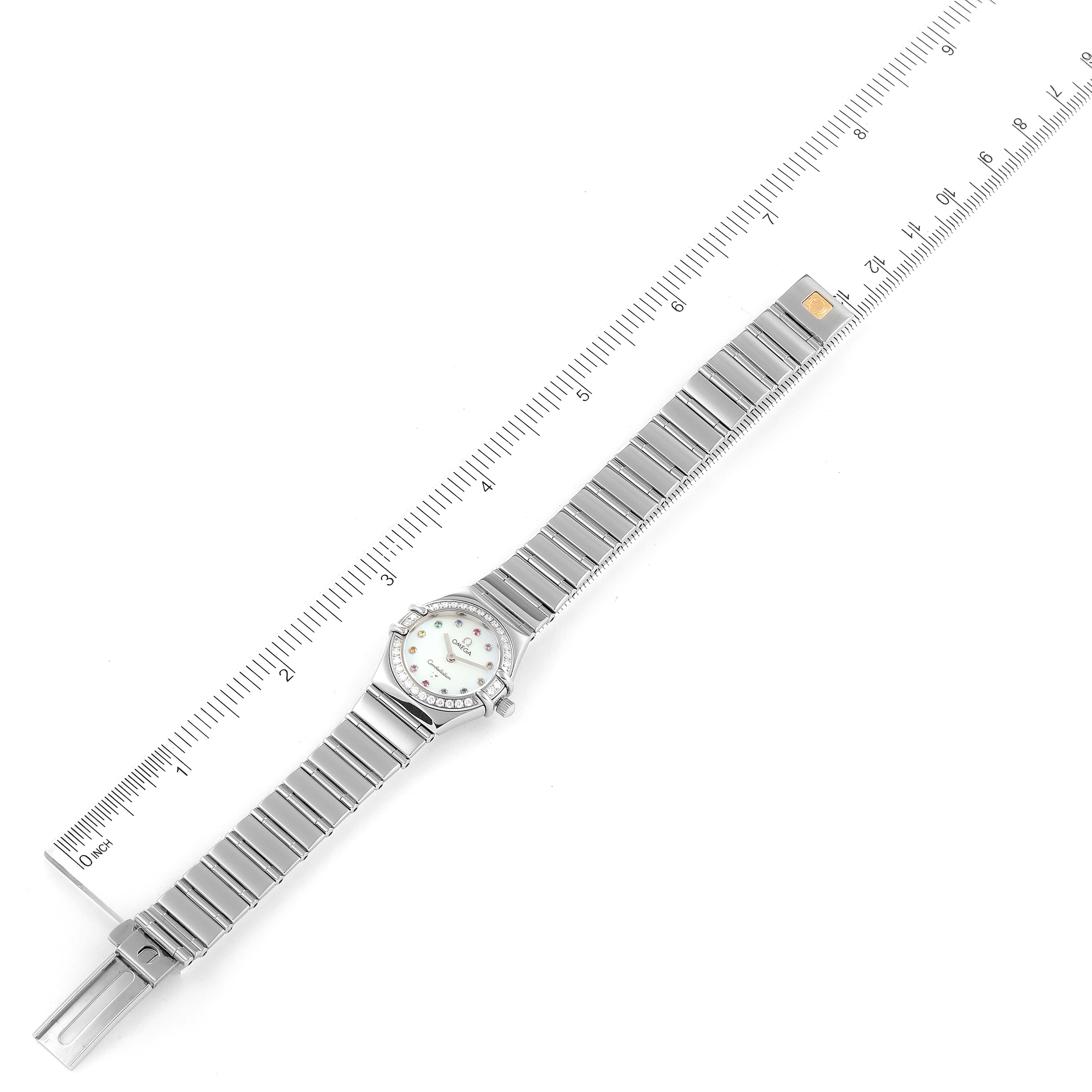 The image shows the Omega 1465.79.00 Women
s Stainless Steel Mother of Pearl Dial 1465.79.00 Women
s Stainless Steel Mother of Pearl Dial Constellation Iris My Choice Steel Multi Stone Ladies Watch 1465.79.00 laid flat next to a ruler for measurement.