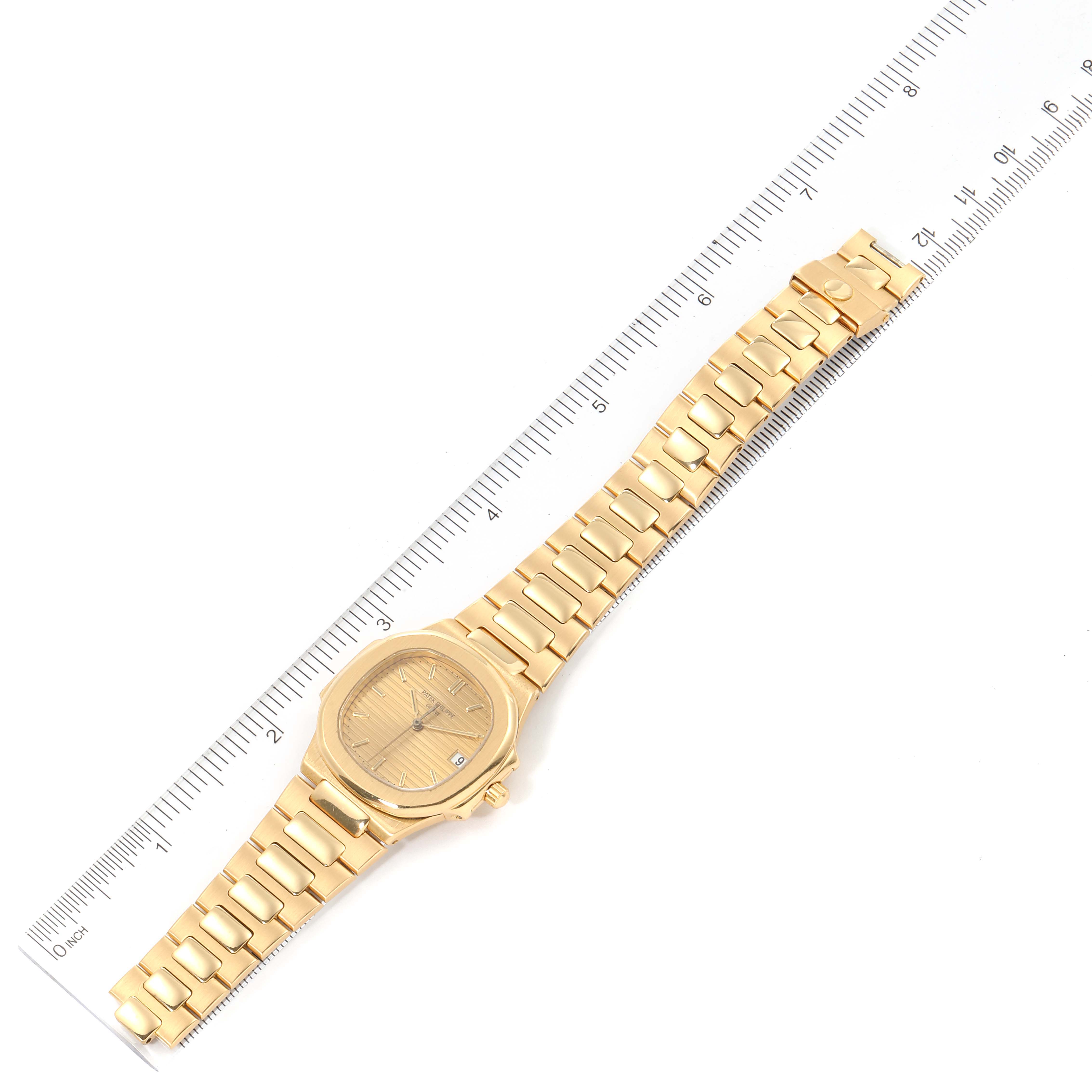The image shows a top-down view of a Patek Philippe Nautilus 3900/1J Women's Yellow Gold Champagne Dial 3900/1J Women's Yellow Gold Champagne Dial watch alongside a ruler for scale.