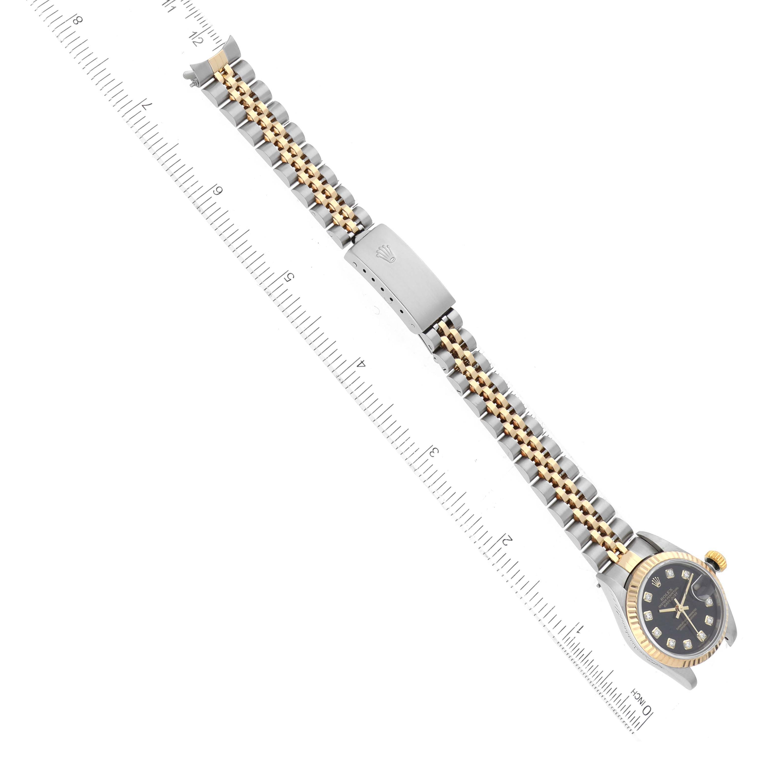 The image shows an overhead view of a Rolex Datejust 79173 Women's Stainless Steel Black Dial 79173 Women's Stainless Steel Black Dial watch, including its bracelet and clasp, alongside a measuring ruler.