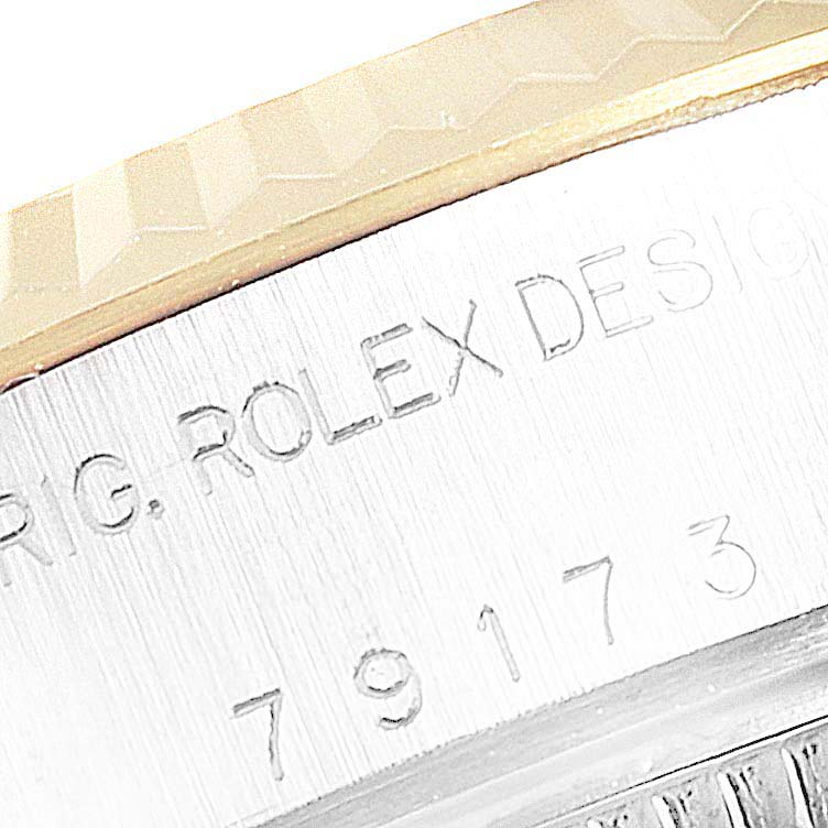 The image shows a close-up of the serial number engraving on the Rolex Datejust 79173 Women's Steel and Gold (two tone) White Dial 79173 Women's Steel and Gold (two tone) White Dial's case side near the bezel.