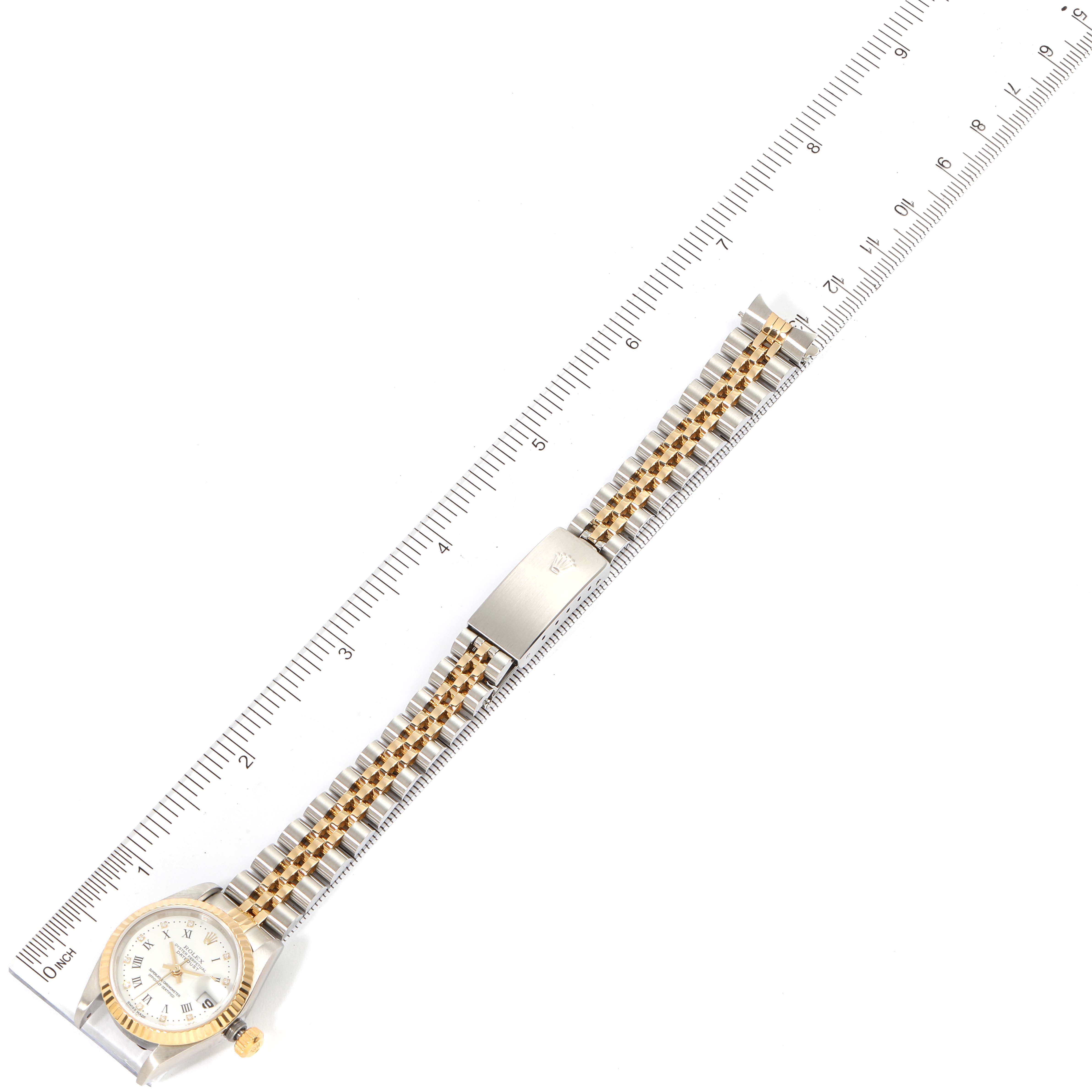 This image shows a top-down view of the Rolex Datejust 79173 Women's Steel and Gold (two tone) White Dial 79173 Women's Steel and Gold (two tone) White Dial watch, showcasing its face, bracelet, and clasp, with a ruler for scale.