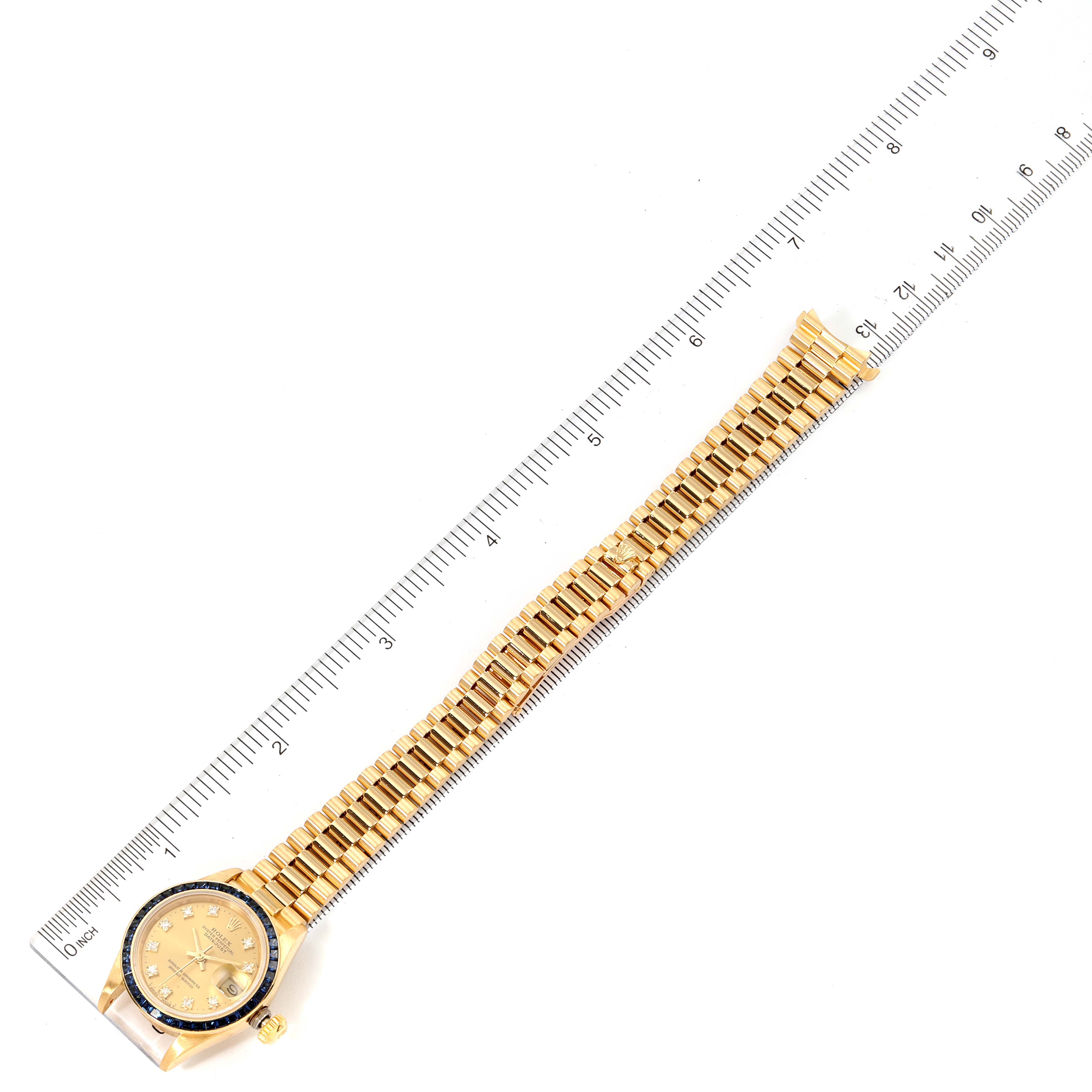 The image shows the Rolex President 69118 Women's Yellow Gold Champagne Dial 69118 Women's Yellow Gold Champagne Dial model watch from a top-down angle along a measuring ruler.