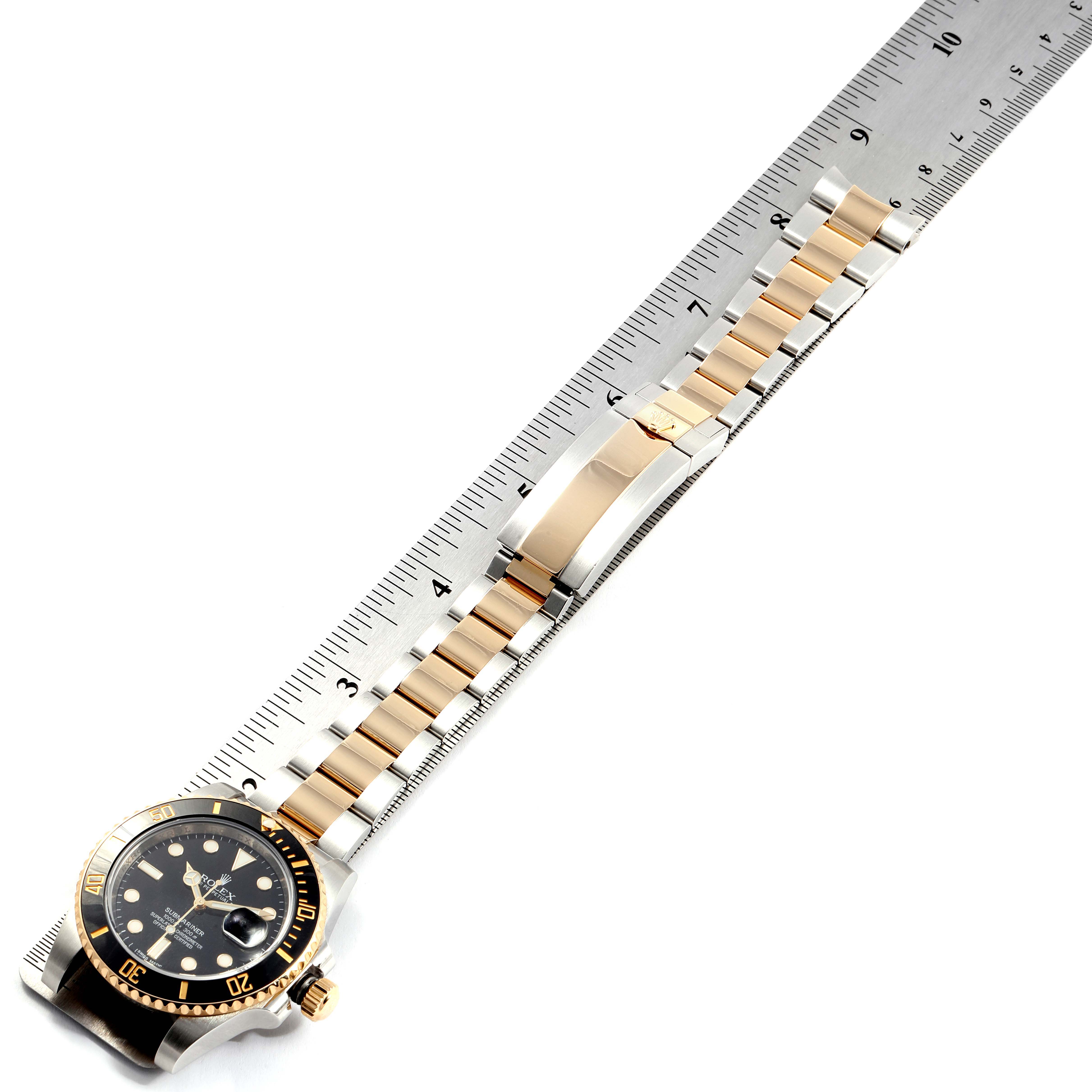 The image shows a Rolex Submariner 116613 Men's Steel and Gold (two tone) Black Dial 116613 Men's Steel and Gold (two tone) Black Dial watch displayed flat against a ruler, highlighting the face and bracelet.