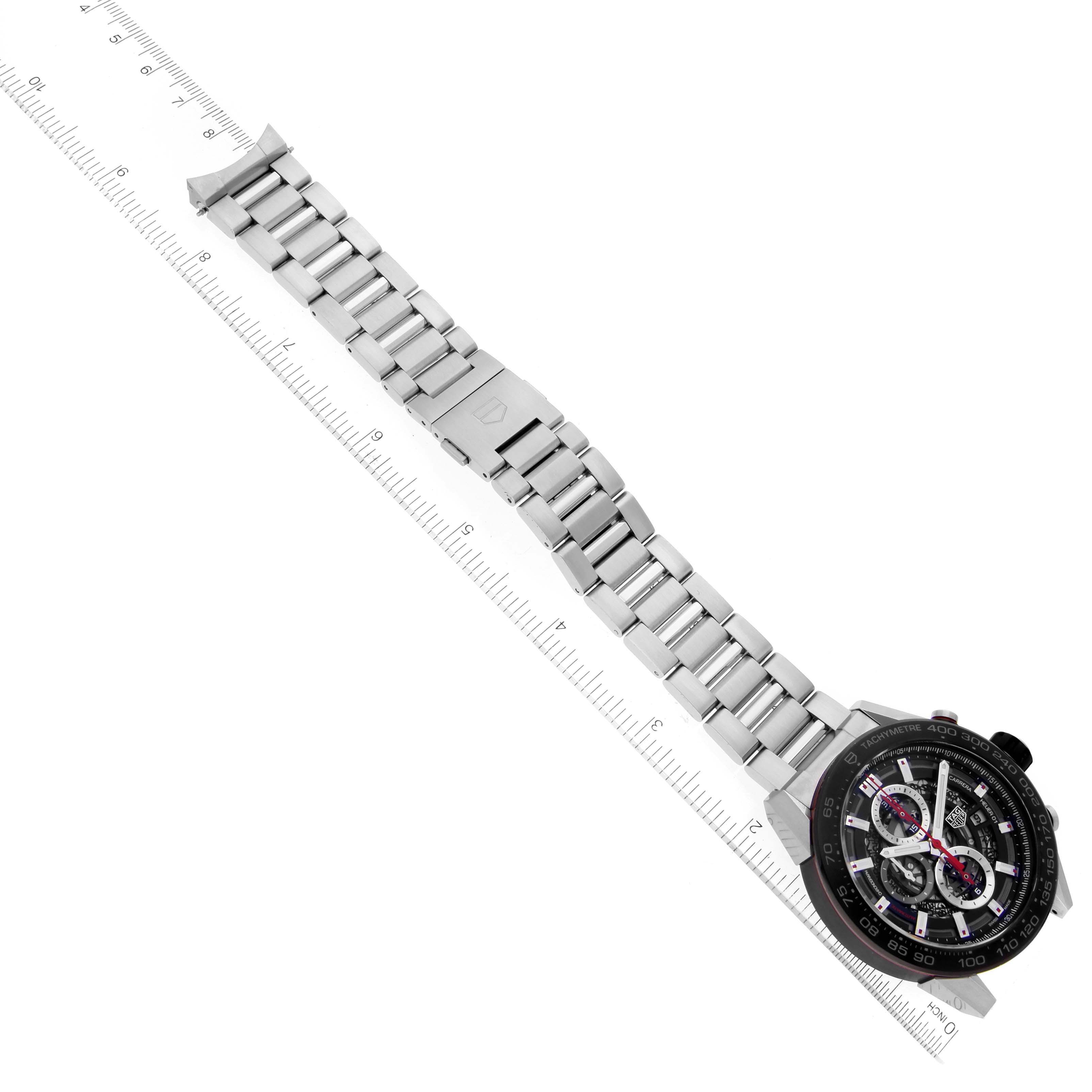 The image shows an angled view of a Tag Heuer Carrera CAR2A1Z.FT6044 Men's Stainless Steel Black Dial CAR2A1Z.FT6044 Men's Stainless Steel Black Dial model watch, featuring its face and stainless steel bracelet placed next to a ruler.
