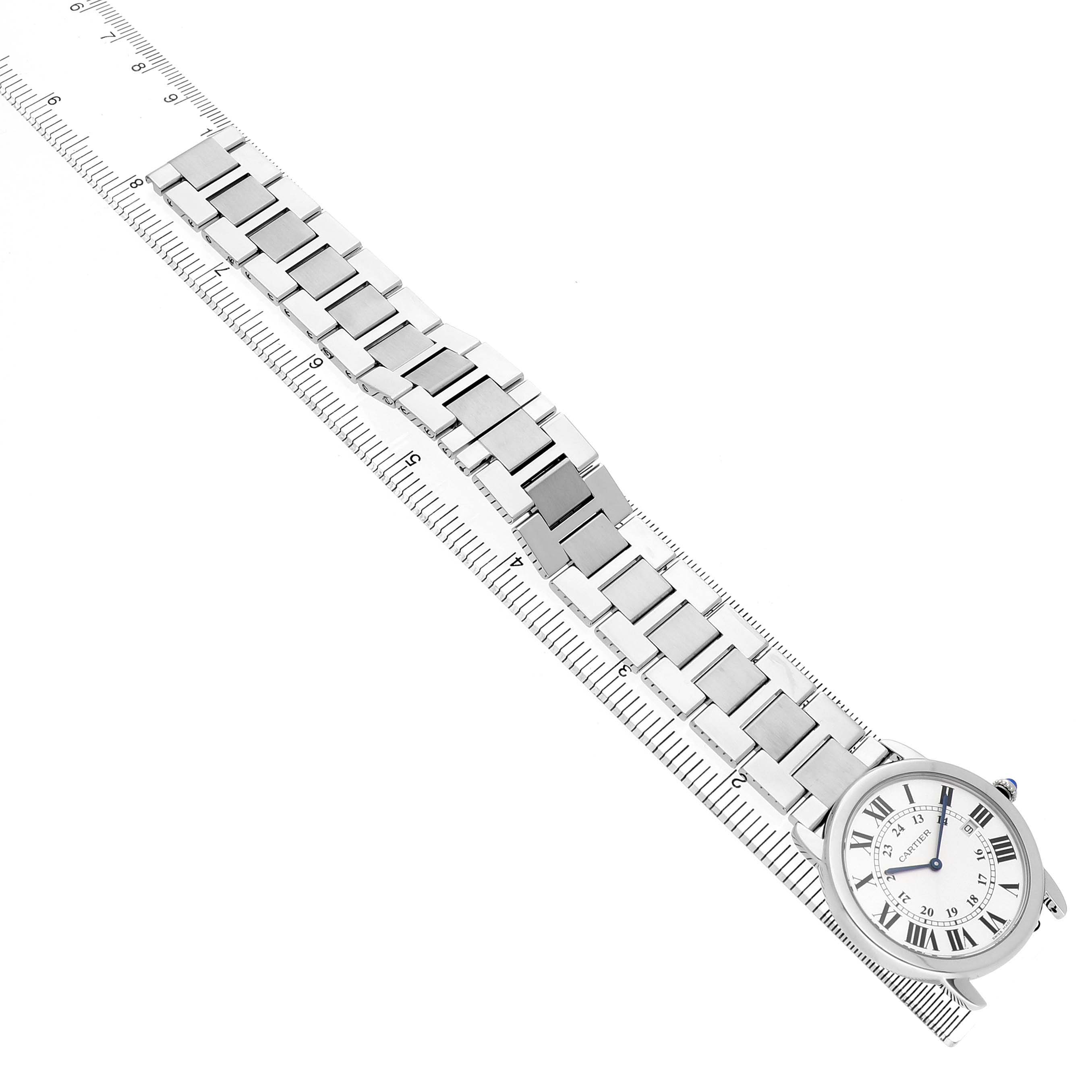 The Cartier Ronde W6701005 Men's Stainless Steel Silver Dial watch is shown at an oblique angle, highlighting the face and metal bracelet against a ruler background.