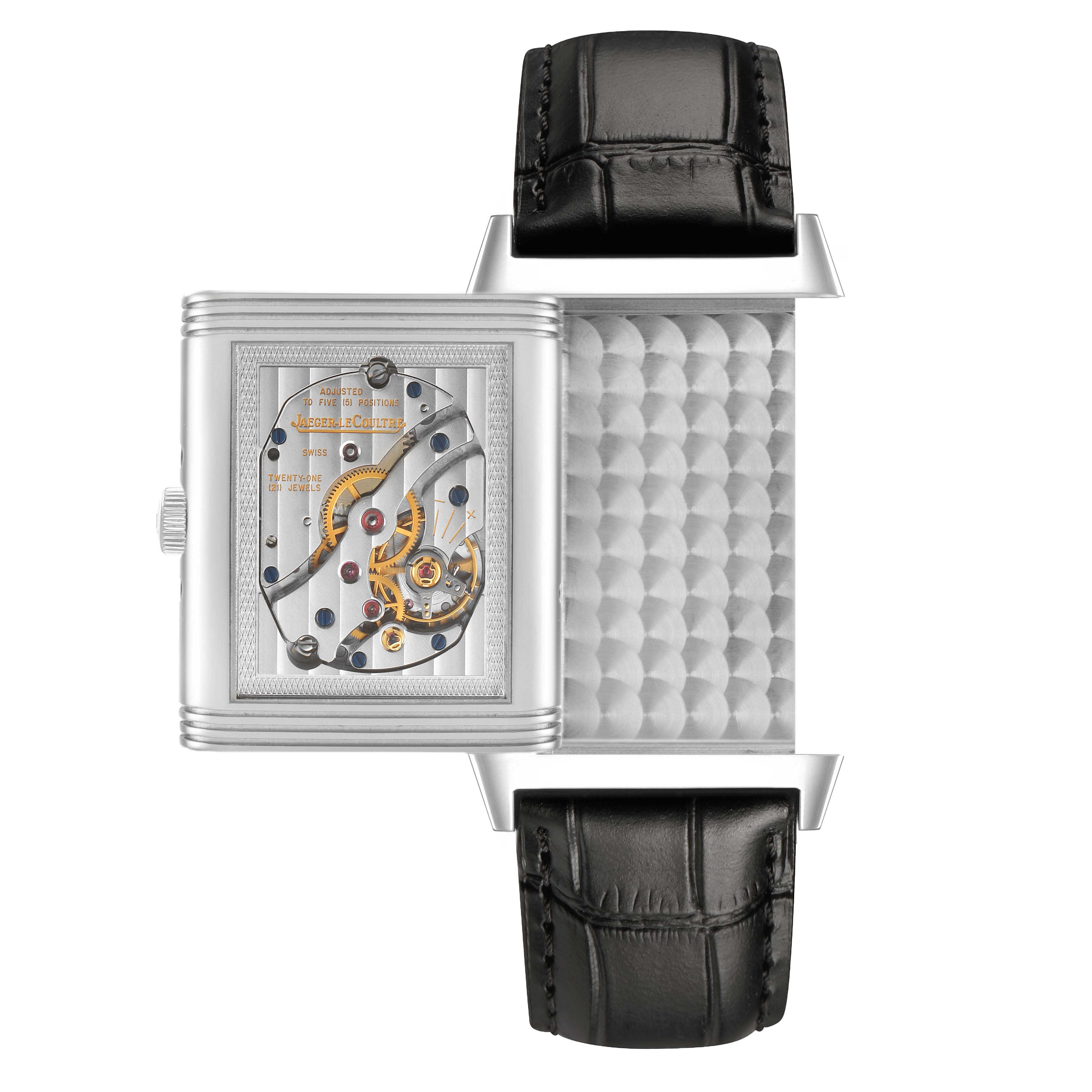 The Jaeger-LeCoultre Reverso watch is shown from the side, displaying its intricate internal mechanics with an open case-back.