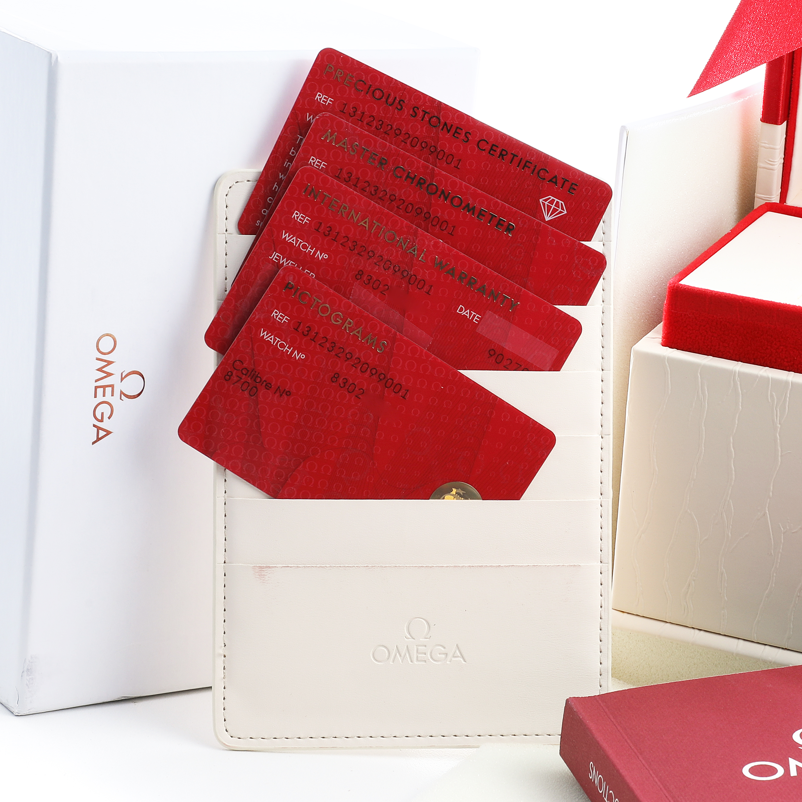 The image shows the accessories of the Omega 131.23.29.20.99.001 Women's Steel and Gold (two tone) Green Dial Constellation 29 Diamond Steel Rose Gold model, including cards and a box.