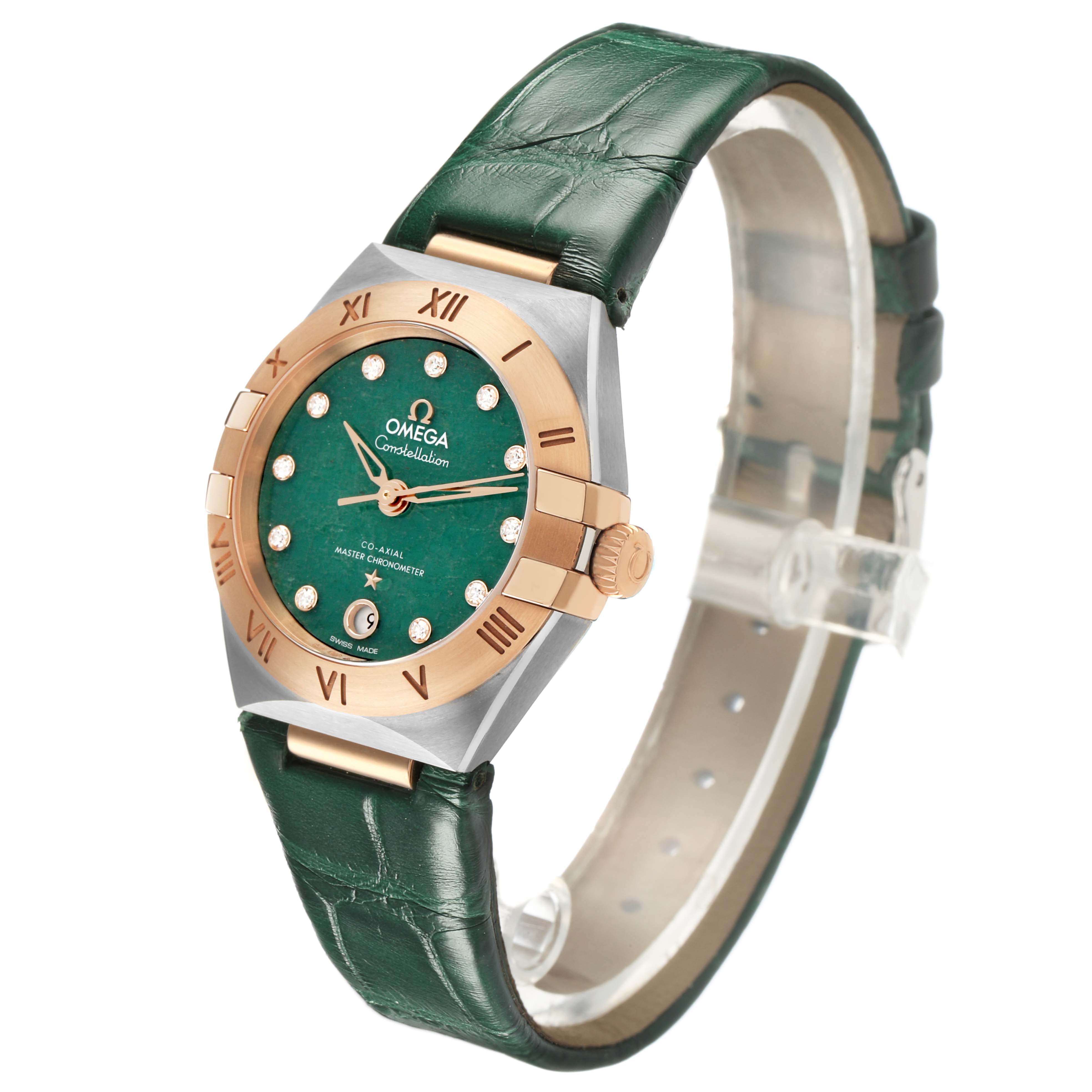 The image shows an Omega 131.23.29.20.99.001 Women's Steel and Gold (two tone) Green Dial Constellation 29 Diamond Steel Rose Gold watch at an angle highlighting the green dial and leather strap.