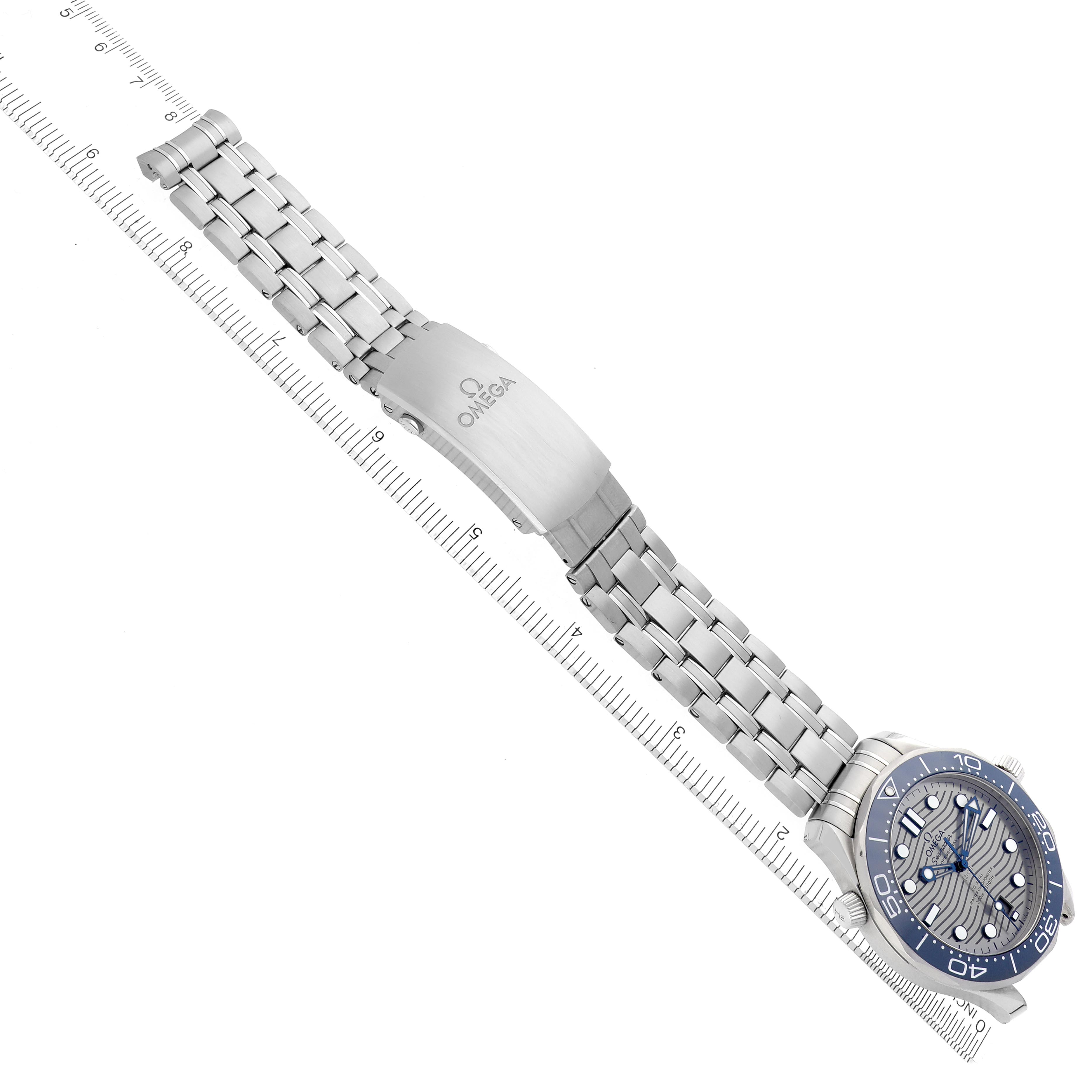 The Omega Seamaster 210.30.42.20.06.001 Men's Stainless Steel Grey Dial 210.30.42.20.06.001 Men's Stainless Steel Grey Dial watch is shown at an angle with a full view of the bracelet, clasp, and face, aligned beside a ruler.