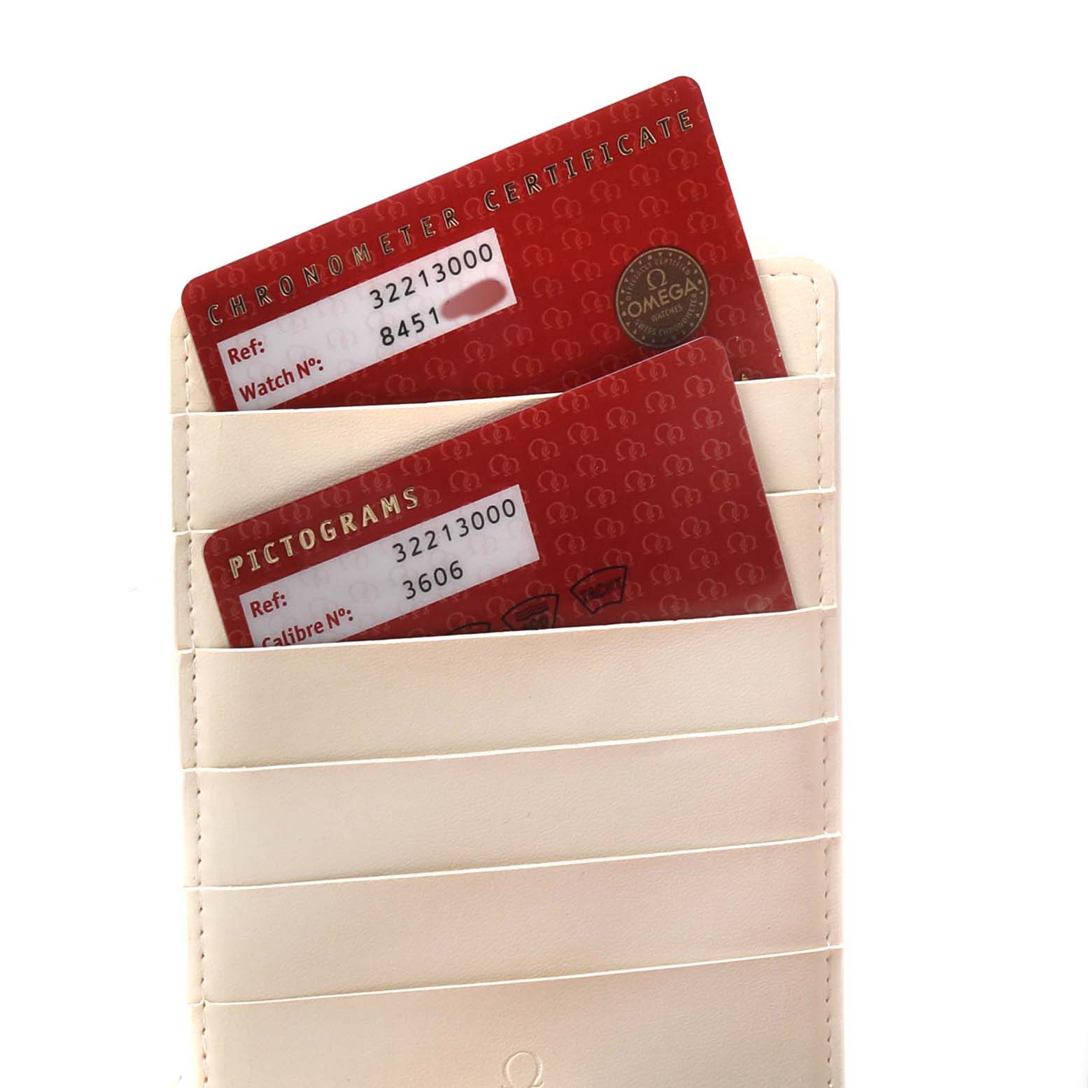 The image shows two red certification cards for an Omega Speedmaster 3221.30.00 Men's Stainless Steel Silver Dial, placed in a cream leather card holder.