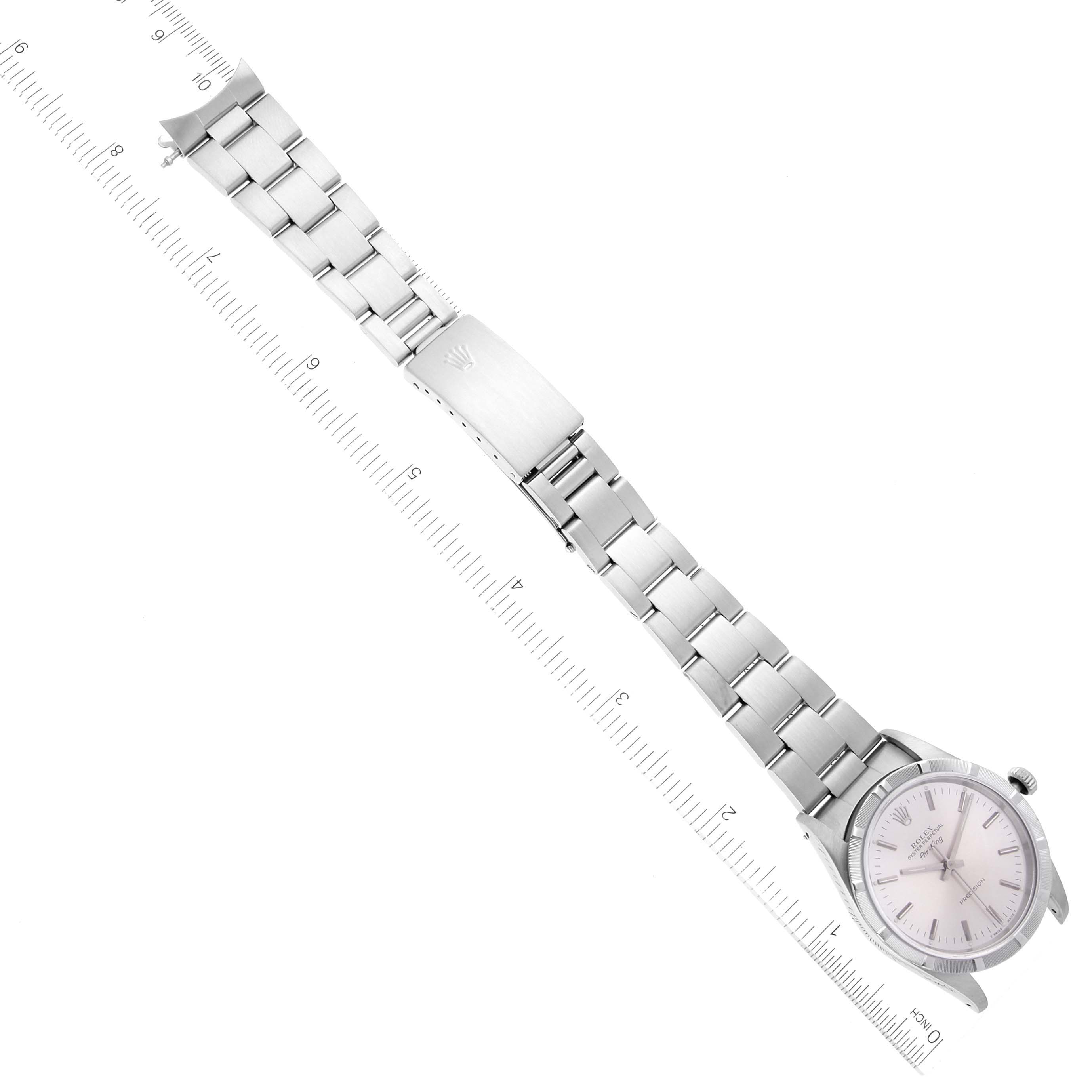 This image shows the Rolex Air-King 14010 Men's Stainless Steel Silver Dial 14010 Men's Stainless Steel Silver Dial watch laid flat with a focus on the bracelet, clasp, and dial alongside a ruler for scale.