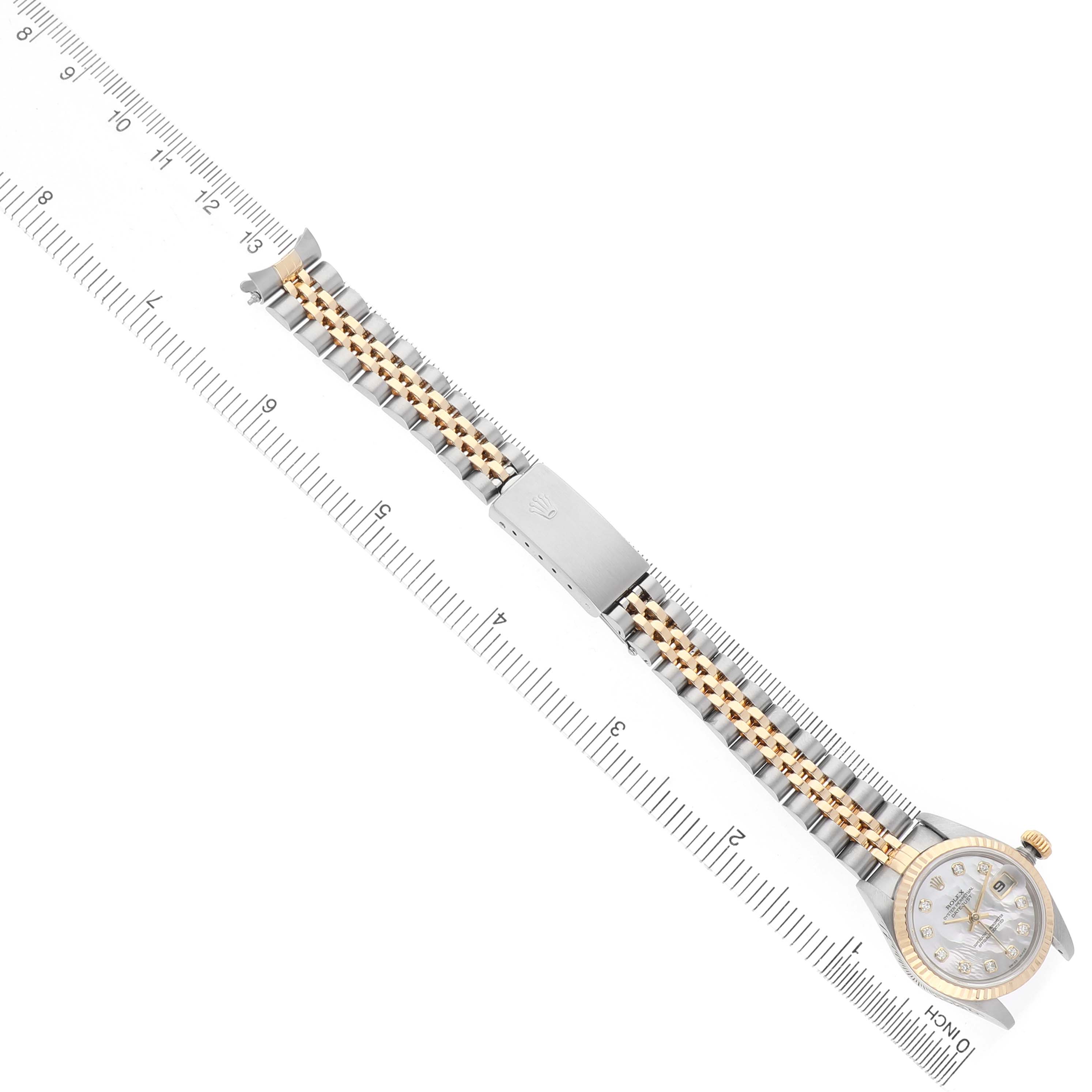 The Rolex Datejust 79173 Women's Steel and Gold (two tone) Mother of Pearl Dial watch is shown from a top-down angle, displaying the full bracelet and face alongside a ruler for scale.