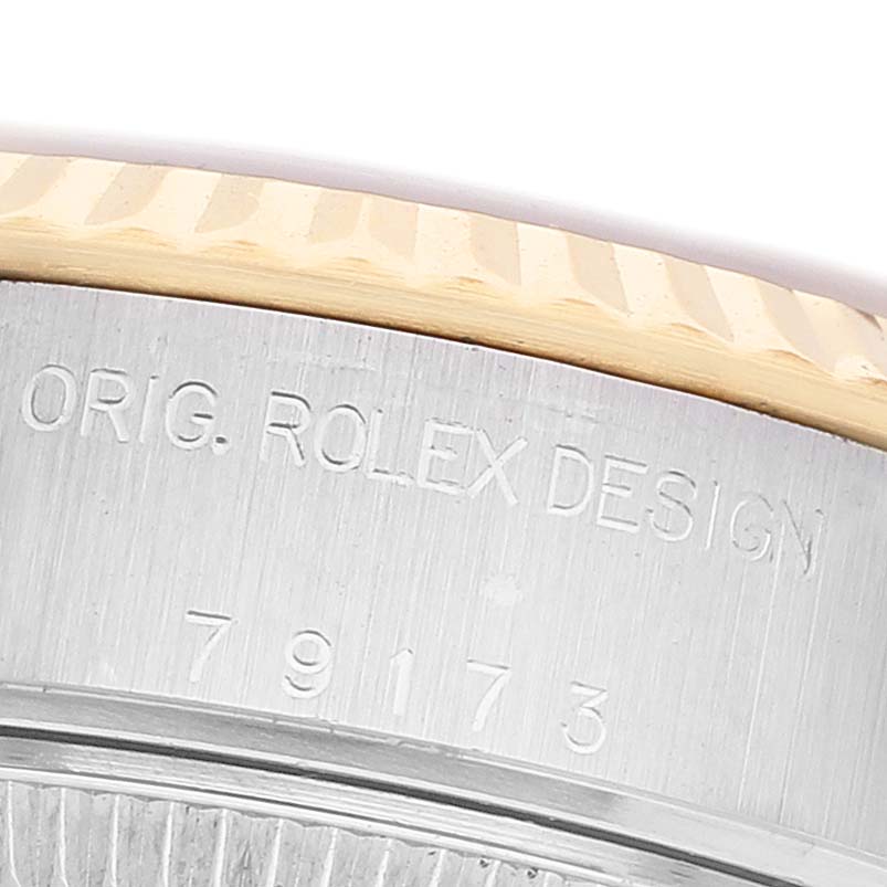 This close-up image of a Rolex Datejust 79173 Women's Steel and Gold (two tone) Mother of Pearl Dial shows the side of the case with engraved markings and a portion of the fluted bezel.