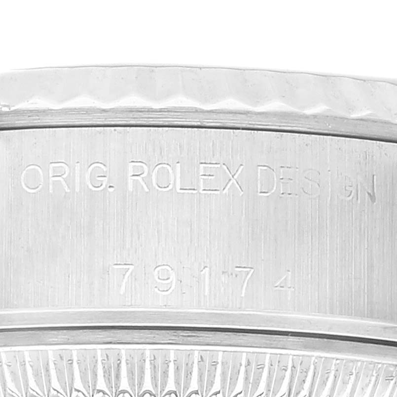 This is a close-up shot of the side of a Rolex Datejust 79174 Women's Stainless Steel White Dial 79174 Women's Stainless Steel White Dial watch, showcasing the engraved model number and "ORIG. ROLEX DESIGN" text.