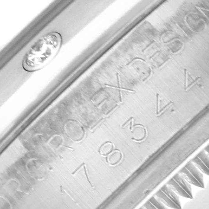 The image shows an angled view of the Rolex Mid-Size 178344 Women's Stainless Steel Pink Dial 178344 Women's Stainless Steel Pink Dial watch's engraved inner bezel and part of the case, highlighting its precise detailing.