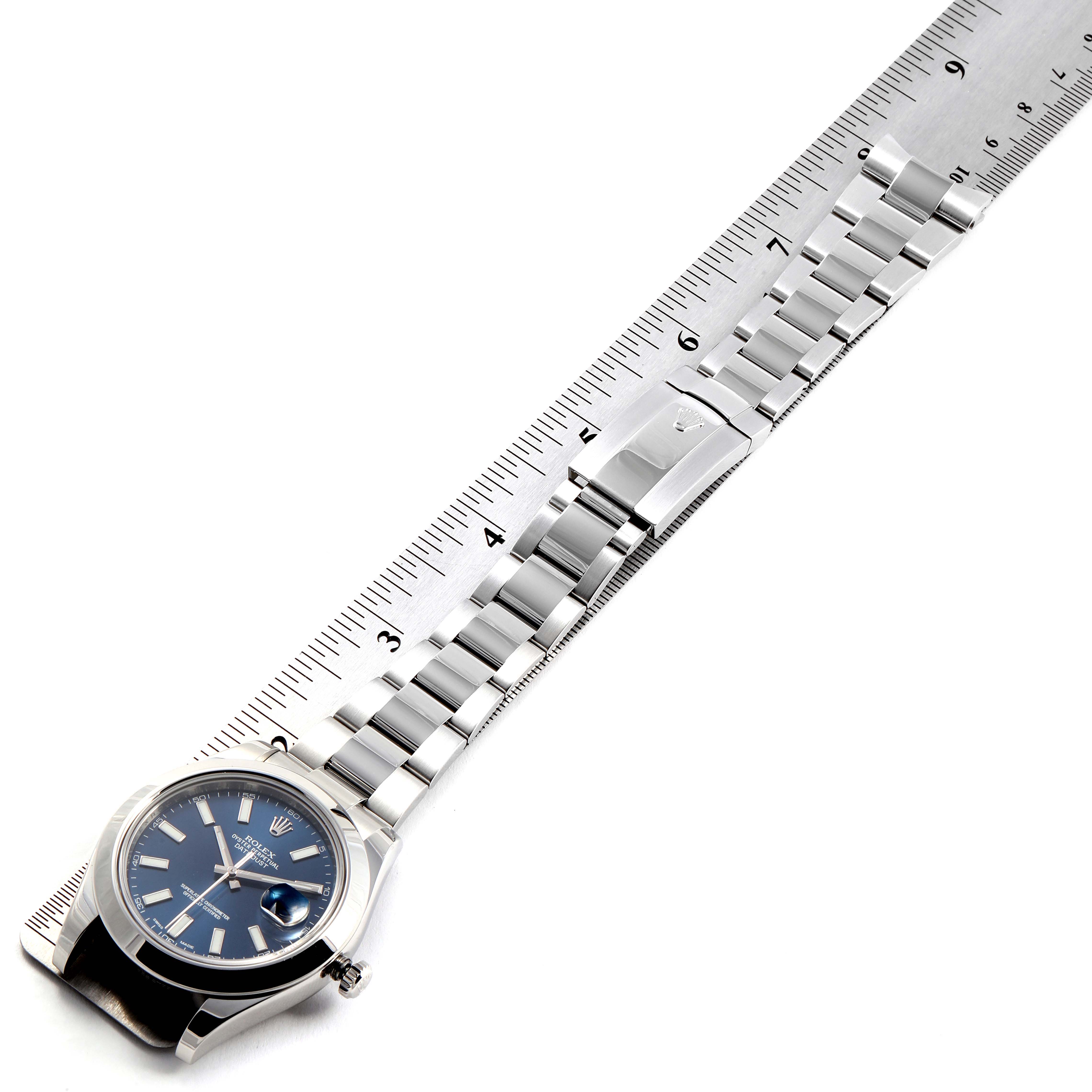 The image shows a Rolex Datejust 41 116300 Men
s Stainless Steel Blue Dial 116300 Men
s Stainless Steel Blue Dial watch laid flat alongside a ruler, highlighting the face, bracelet, and clasp.