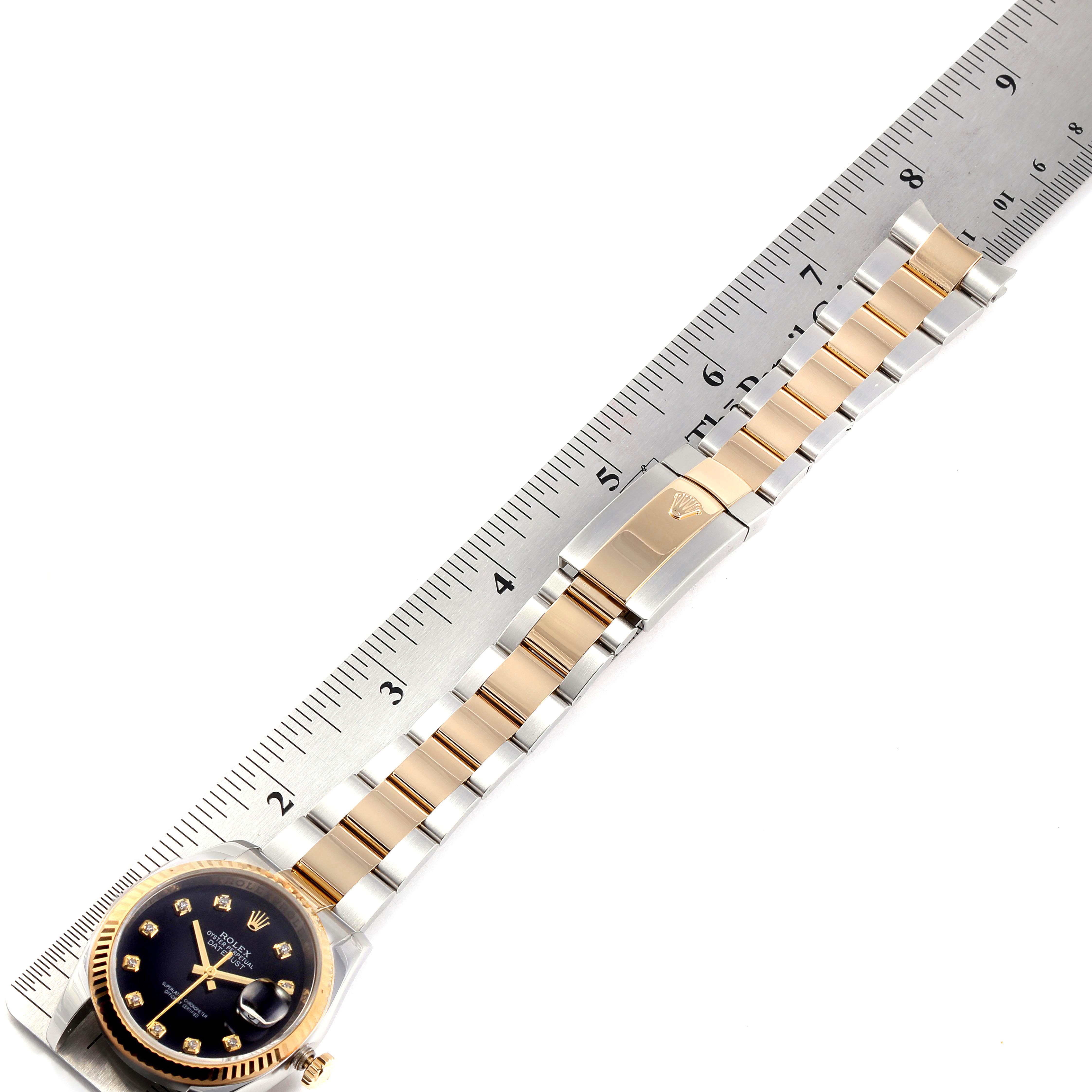 The image shows a top-view angle of a Rolex Datejust 116233 Men's Steel and Gold (two tone) Black Dial 116233 Men's Steel and Gold (two tone) Black Dial watch with its band extended along a ruler.