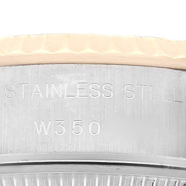 This close-up of the Rolex Datejust 69173 Women's Steel and Gold (two tone) Champagne Dial 69173 Women's Steel and Gold (two tone) Champagne Dial watch shows a portion of the case, highlighting the stainless steel material and some engravings.