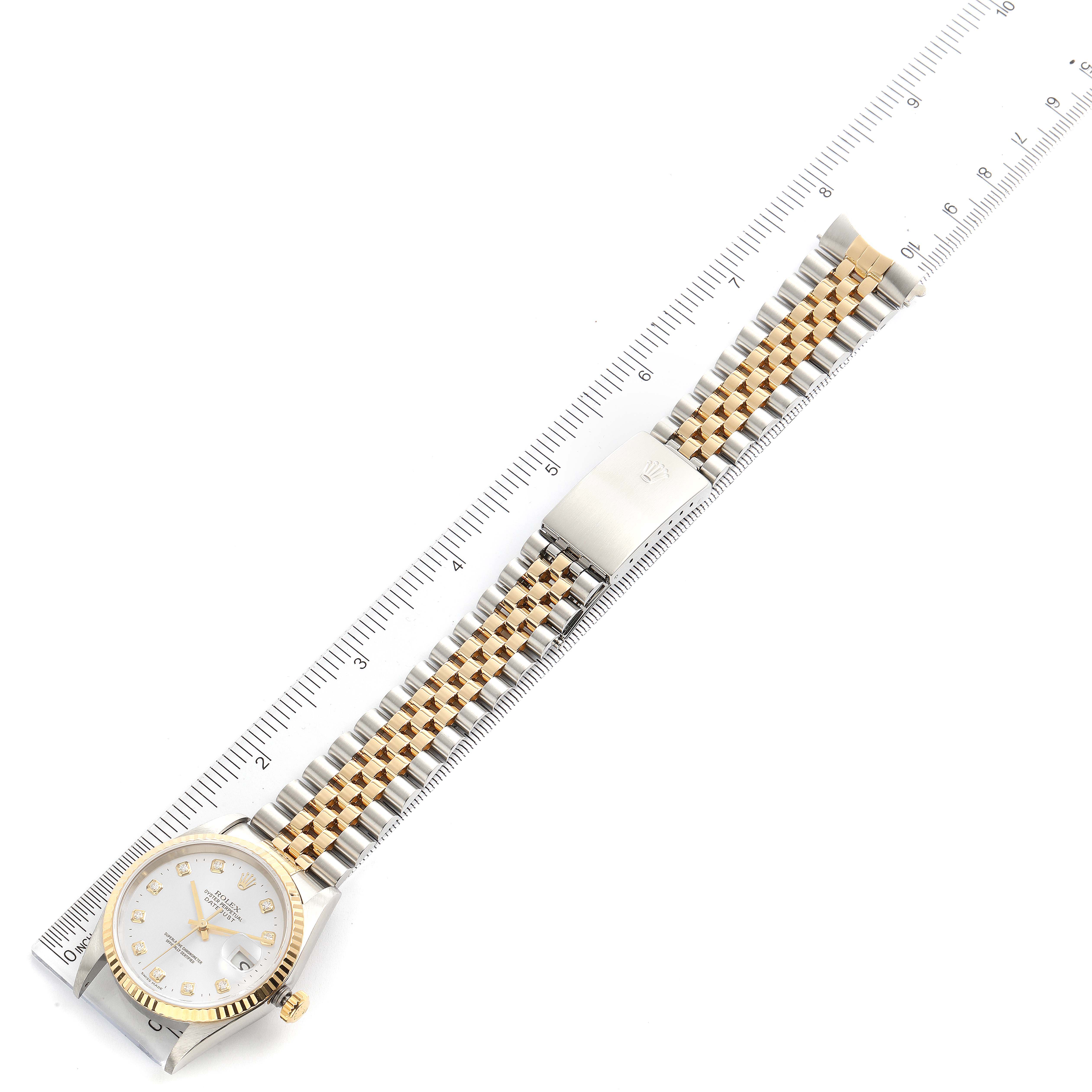 This image shows a Rolex Datejust 16233 Men's Steel and Gold (two tone) Silver Dial 16233 Men's Steel and Gold (two tone) Silver Dial watch laid flat with its two-toned band beside a ruler for measurement.