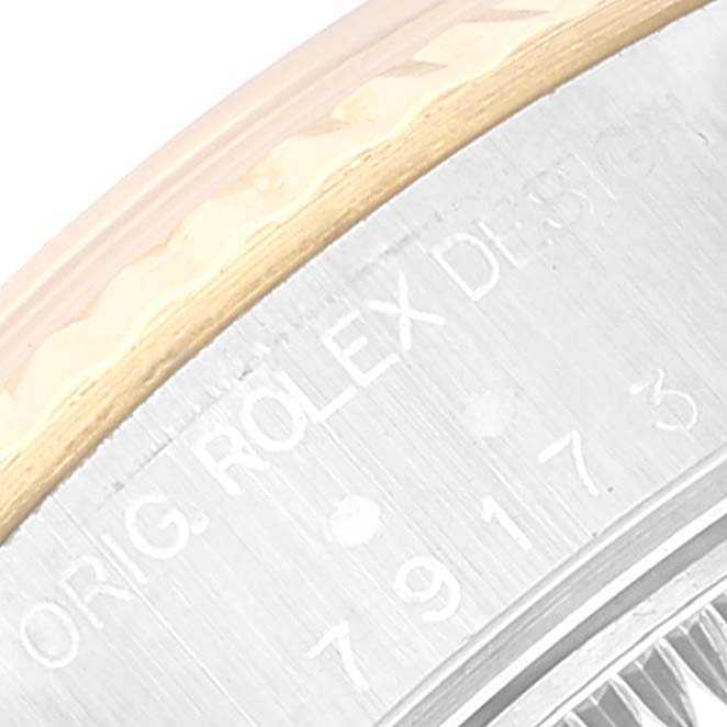 The image shows a close-up of the side case of a Rolex Datejust 79173 Women's Steel and Gold (two tone) Grey Dial 79173 Women's Steel and Gold (two tone) Grey Dial model, displaying part of its engraved text and the edge of the bezel.