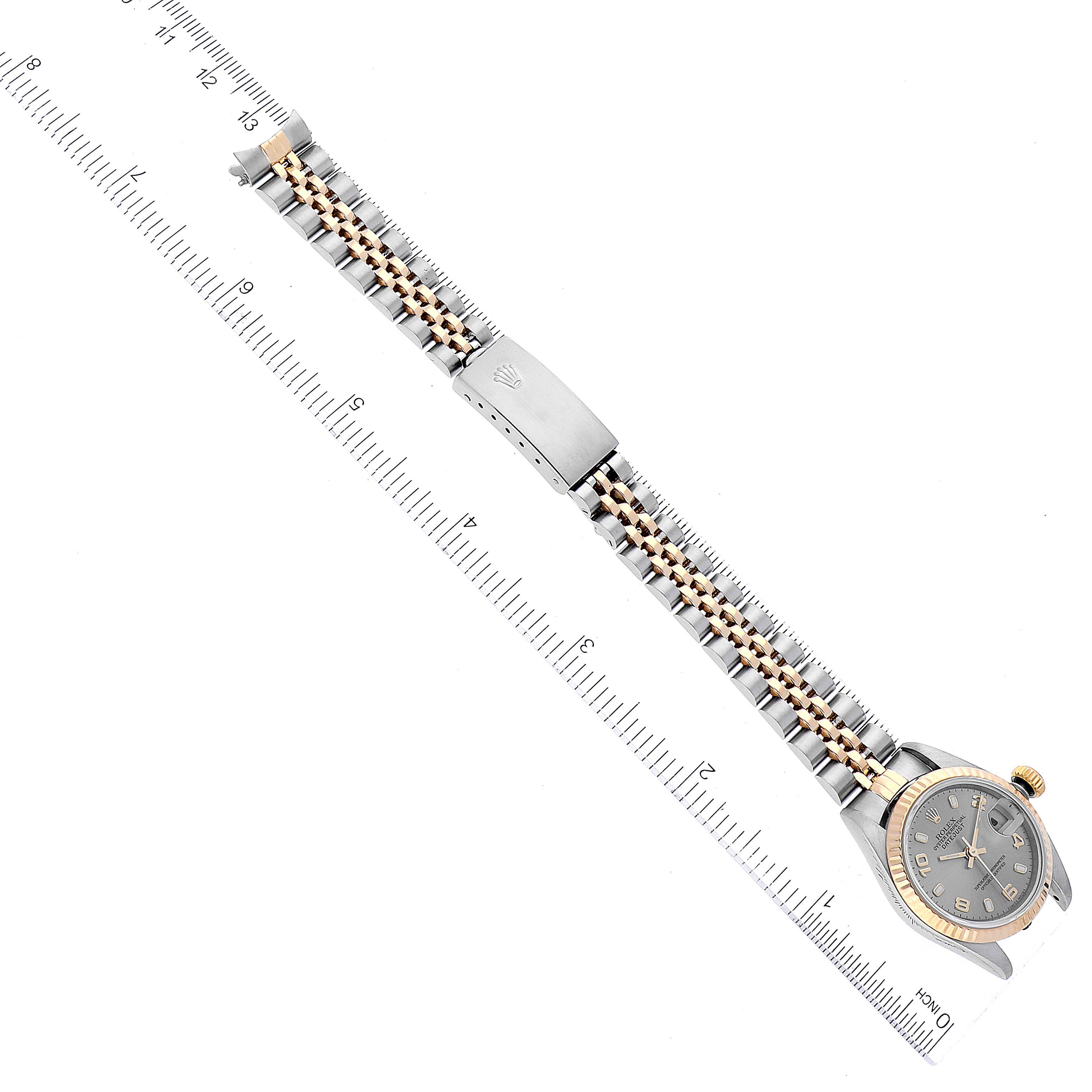 The image shows a top-down view of a Rolex Datejust 79173 Women's Steel and Gold (two tone) Grey Dial 79173 Women's Steel and Gold (two tone) Grey Dial watch with its full bracelet and clasp extended next to a ruler.