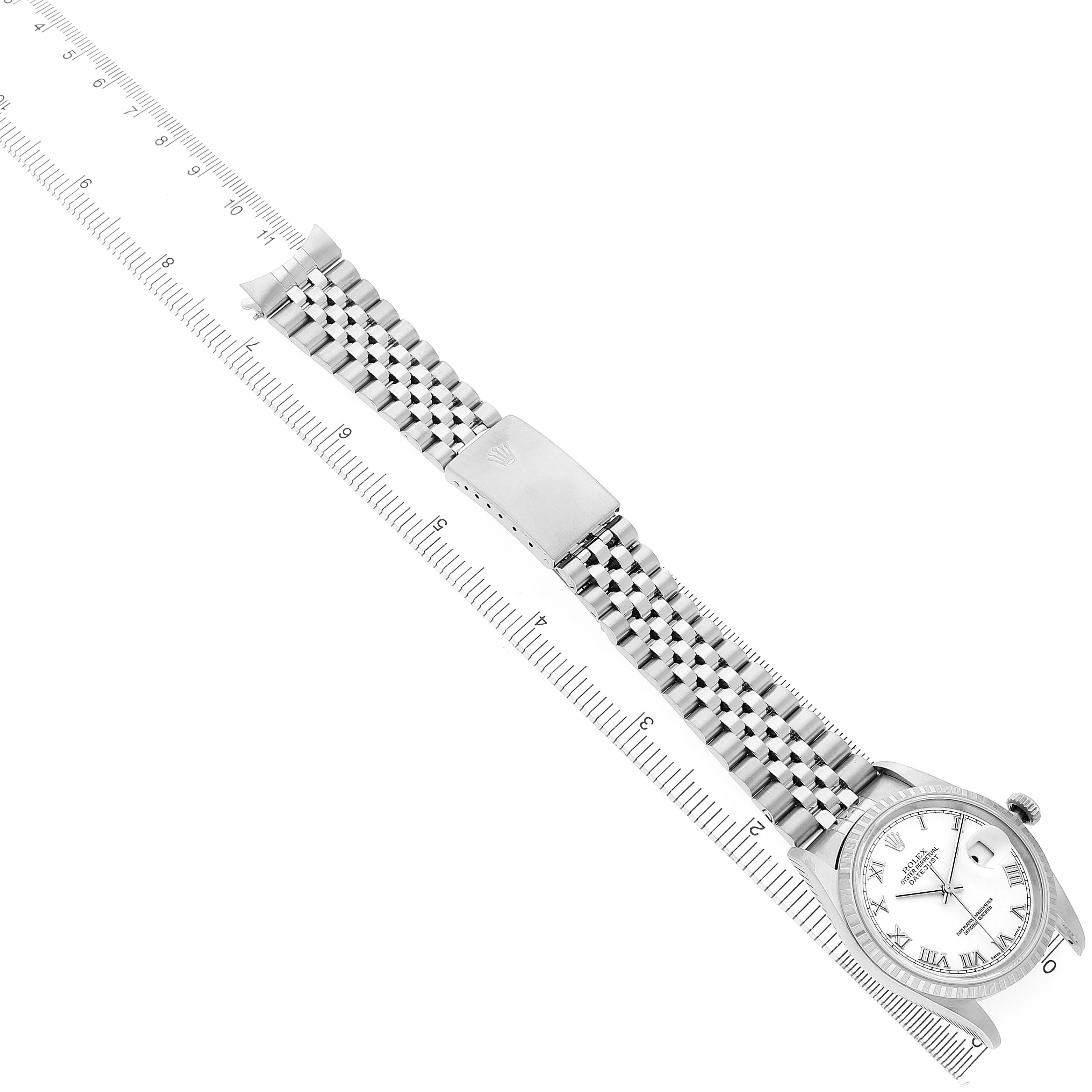 The Rolex Datejust 16220 Men's Stainless Steel White Dial watch is shown from a top angle, displaying the face, bezel, bracelet, and clasp alongside a measuring ruler.