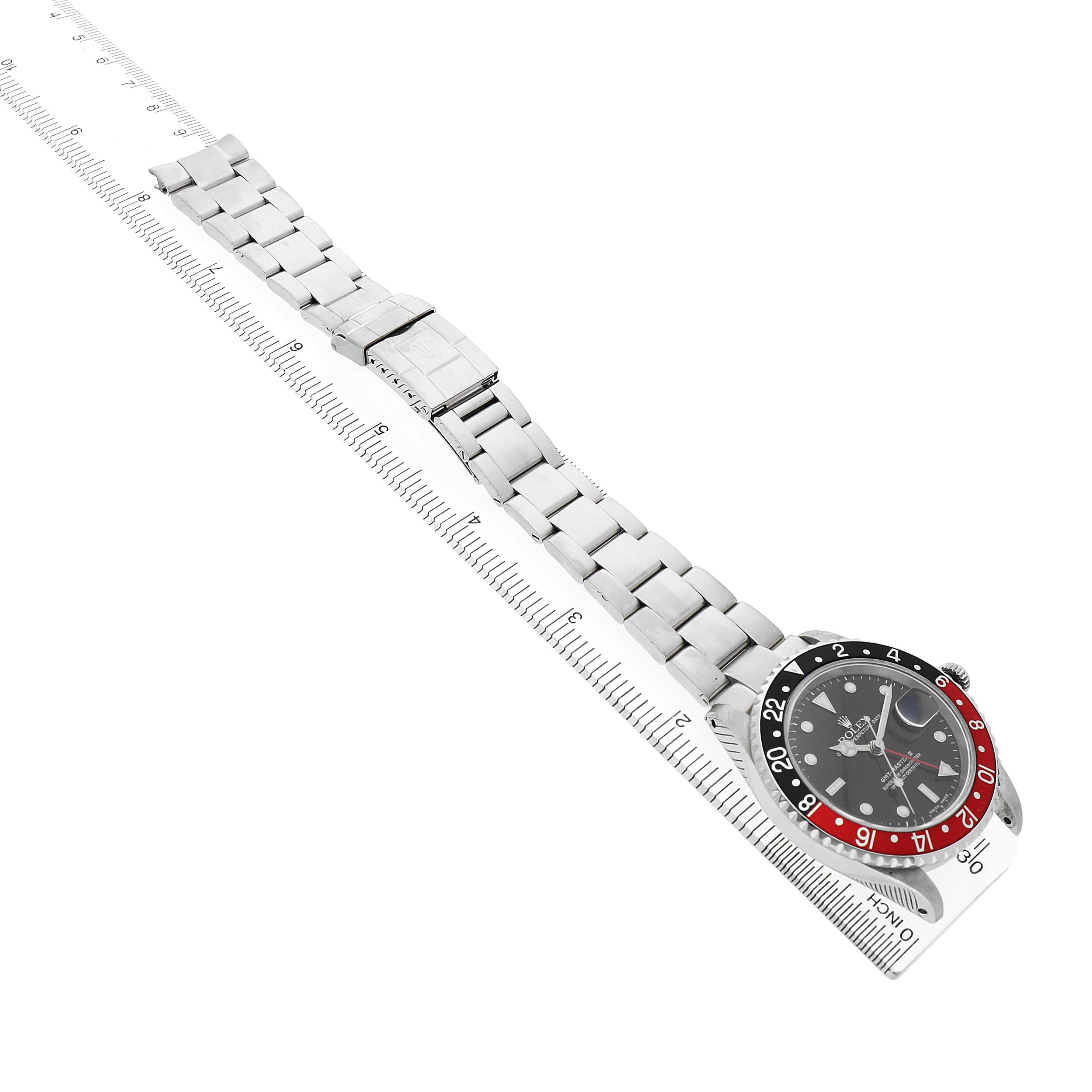 The Rolex GMT-Master 16710 Men's Stainless Steel Black Dial is shown at an angle displaying the bezel, dial, and bracelet, resting atop a ruler.
